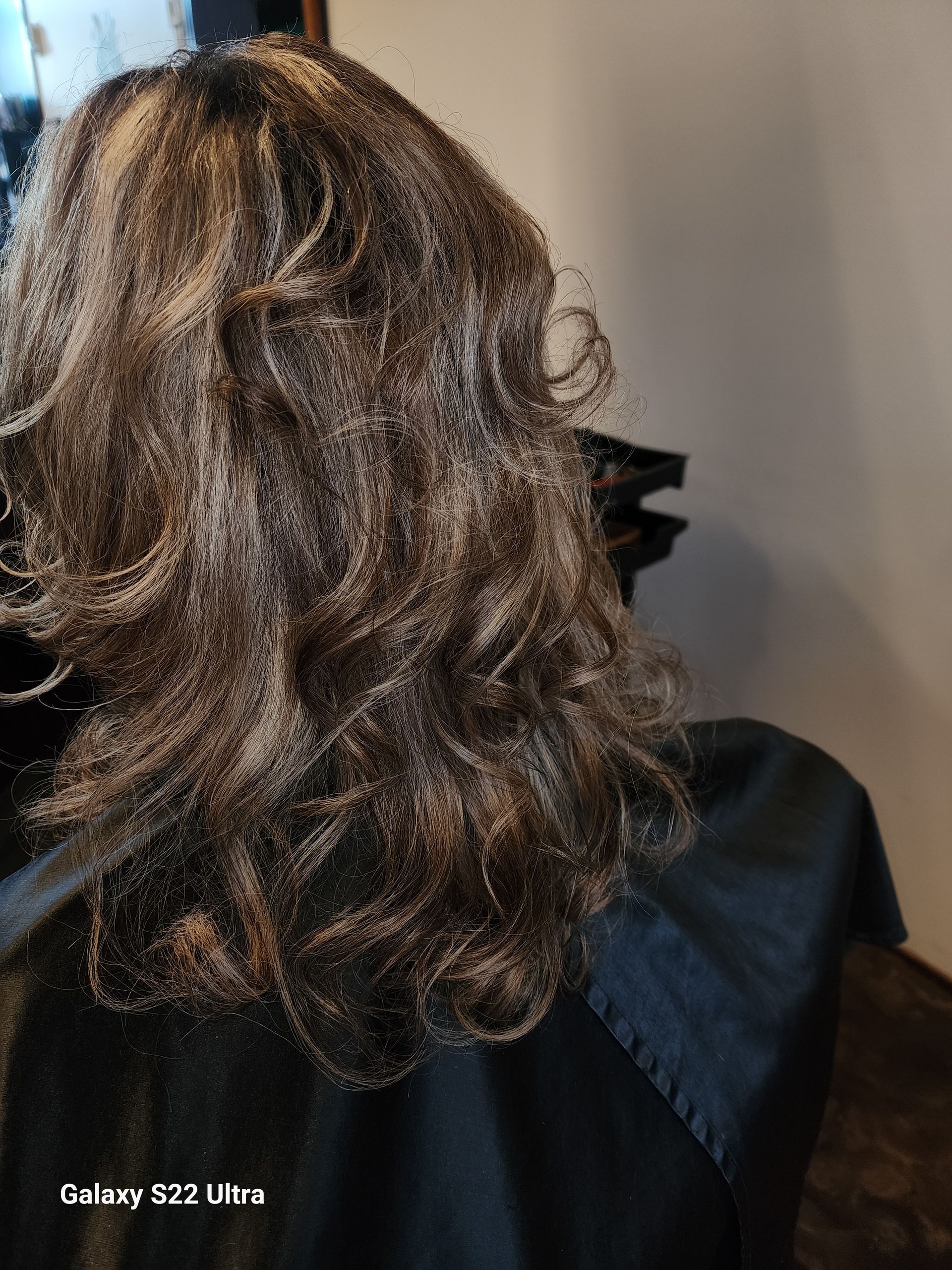 A woman is sitting in front of a mirror with her hair in a ponytail.