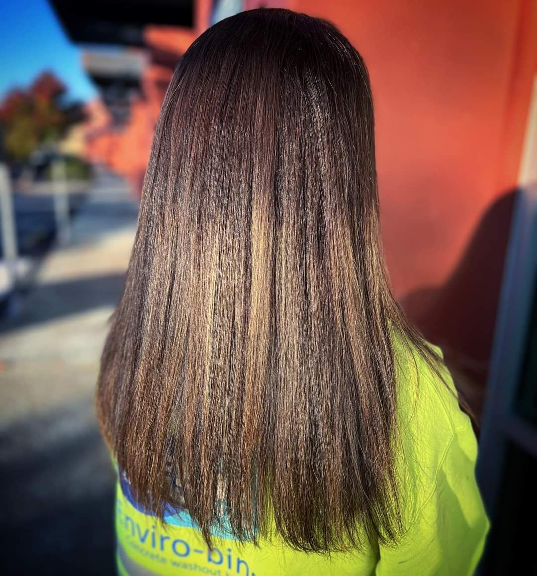 A woman with long brown hair is wearing a yellow shirt that says enviro-bin