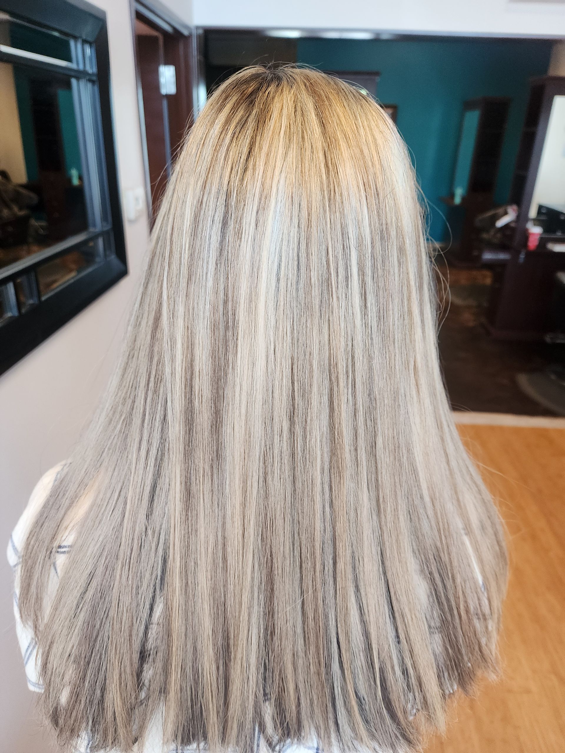 A woman with long blonde hair is standing in front of a mirror