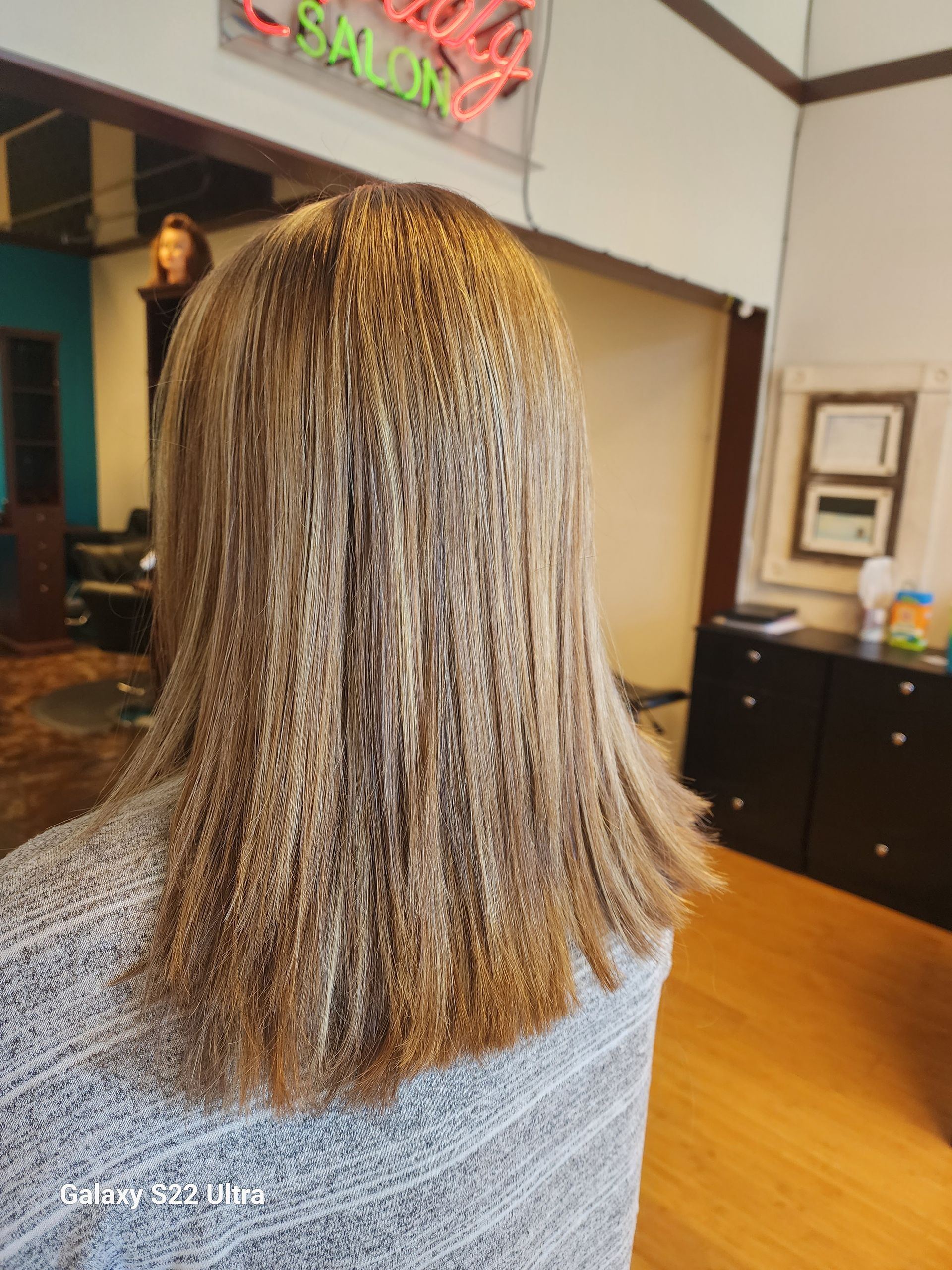 A woman is sitting in front of a sign that says beauty salon