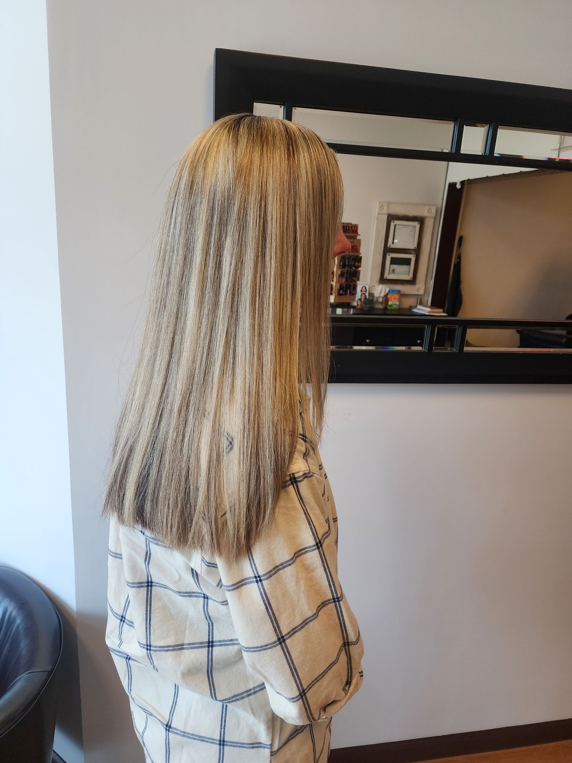 A woman with long blonde hair is standing in front of a mirror.