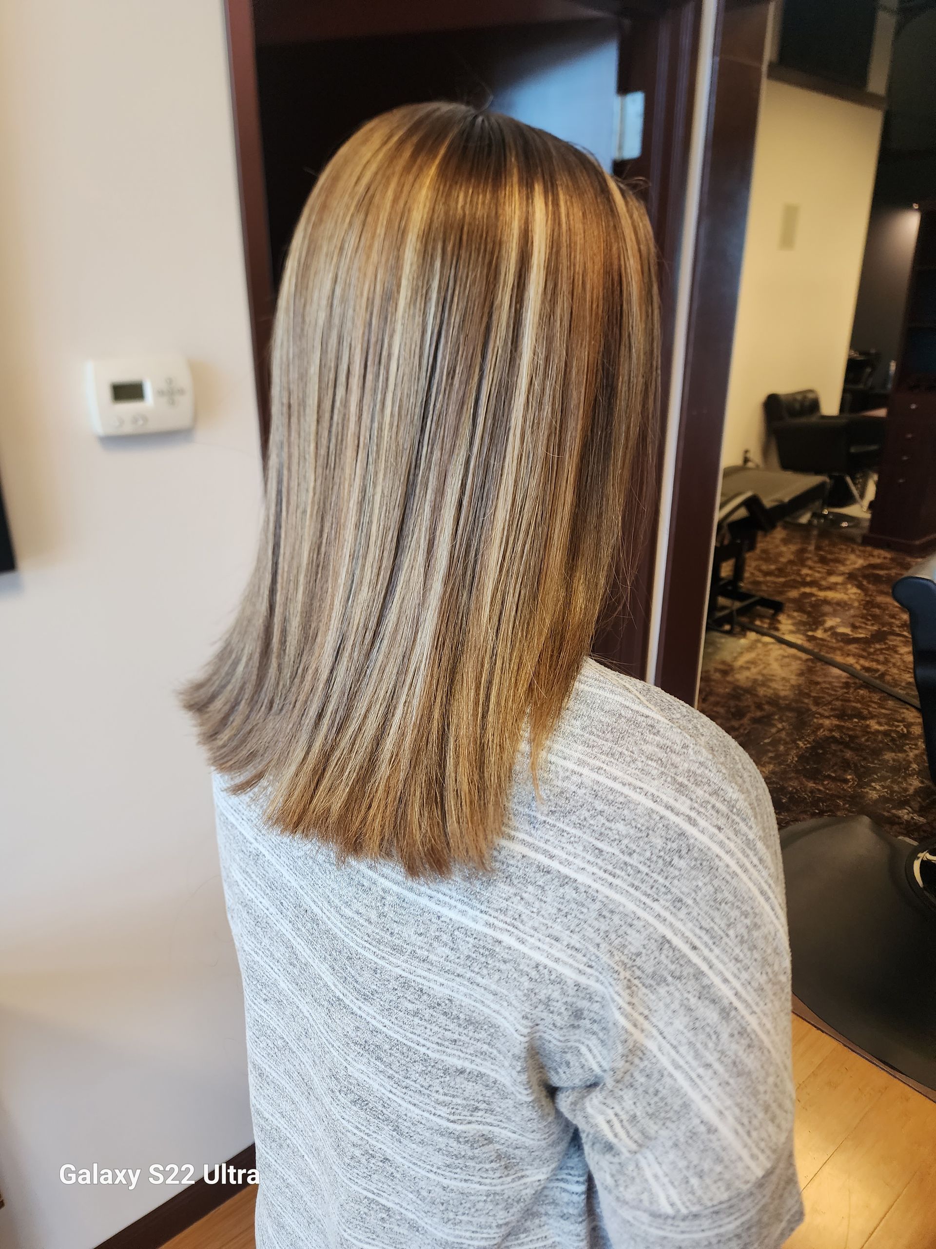 A woman with blonde hair is wearing a gray sweater.