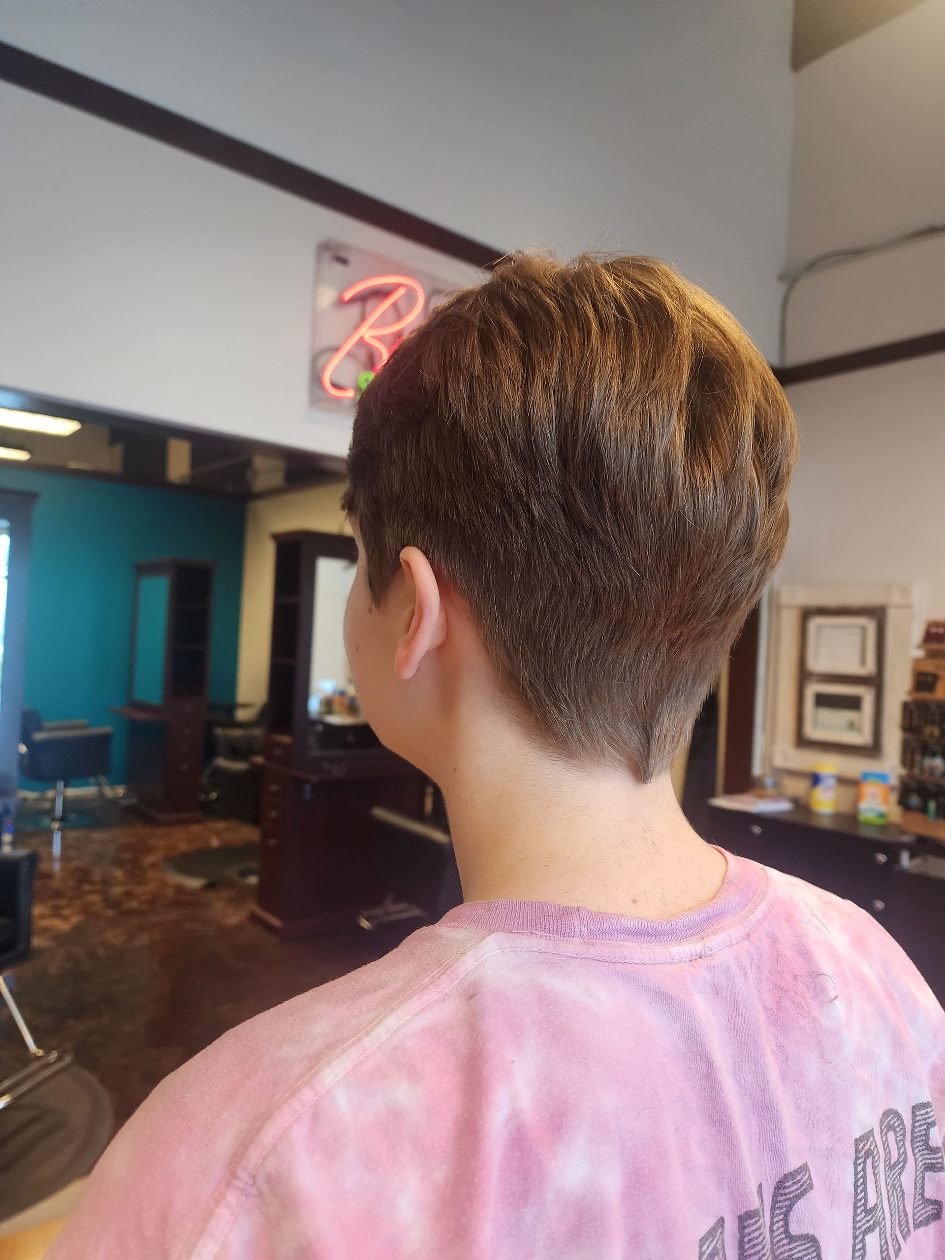 A young boy is getting his hair cut in a salon.