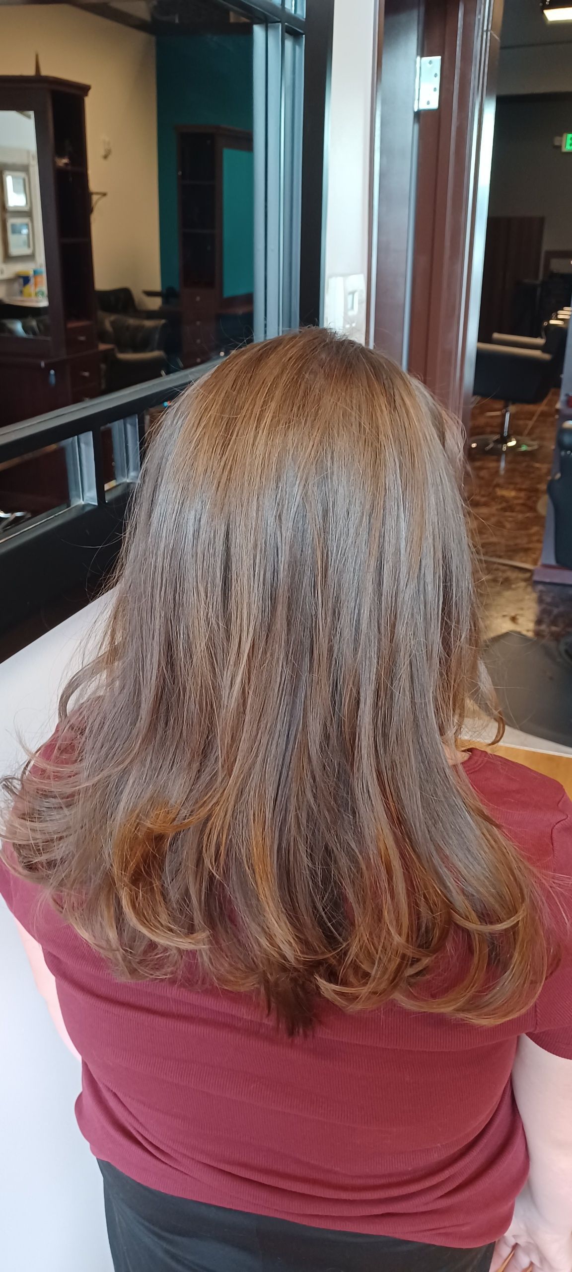 A woman with long hair is sitting in a chair in a salon.