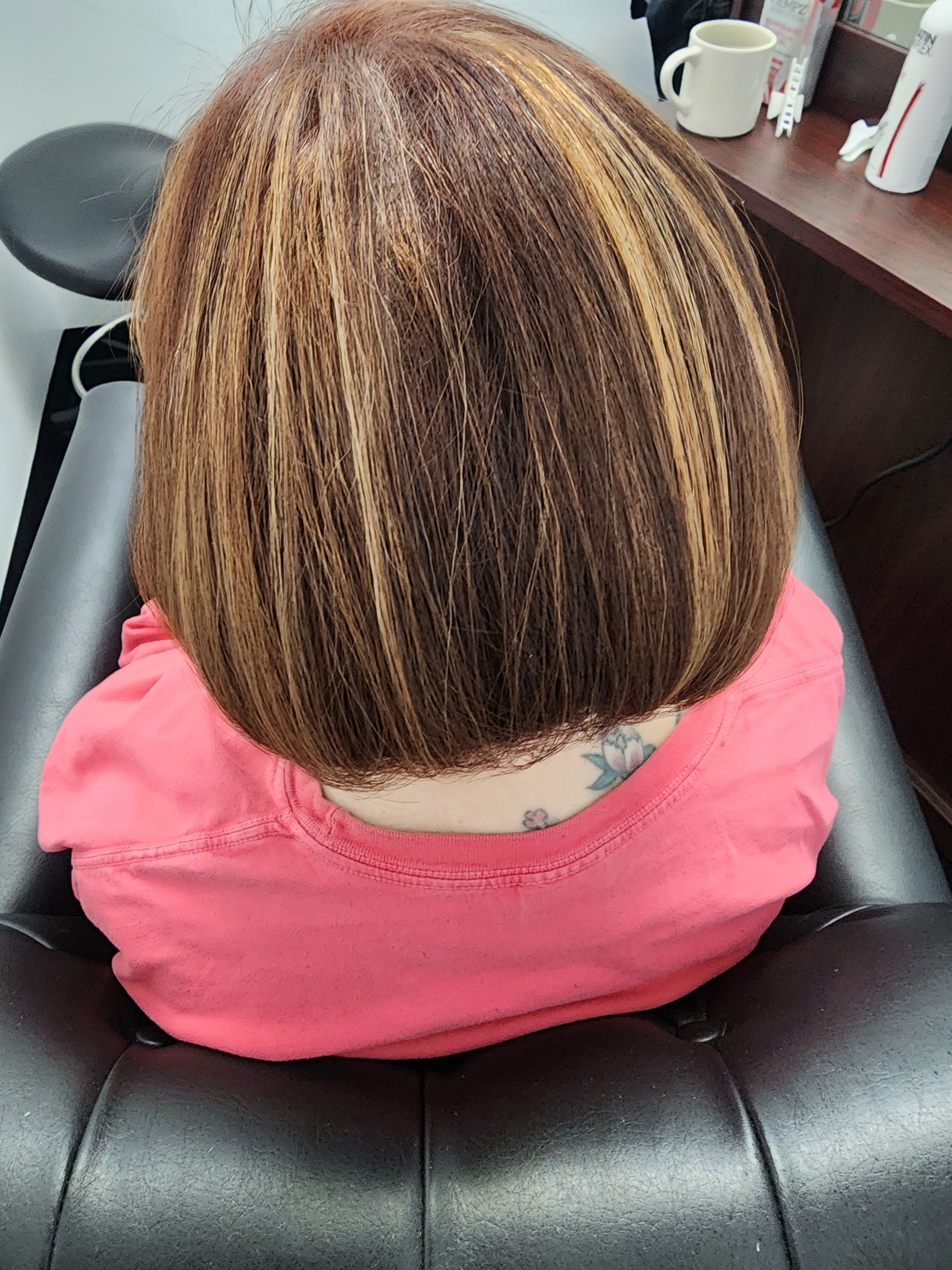 A woman in a pink shirt is sitting in a chair with her back to the camera.