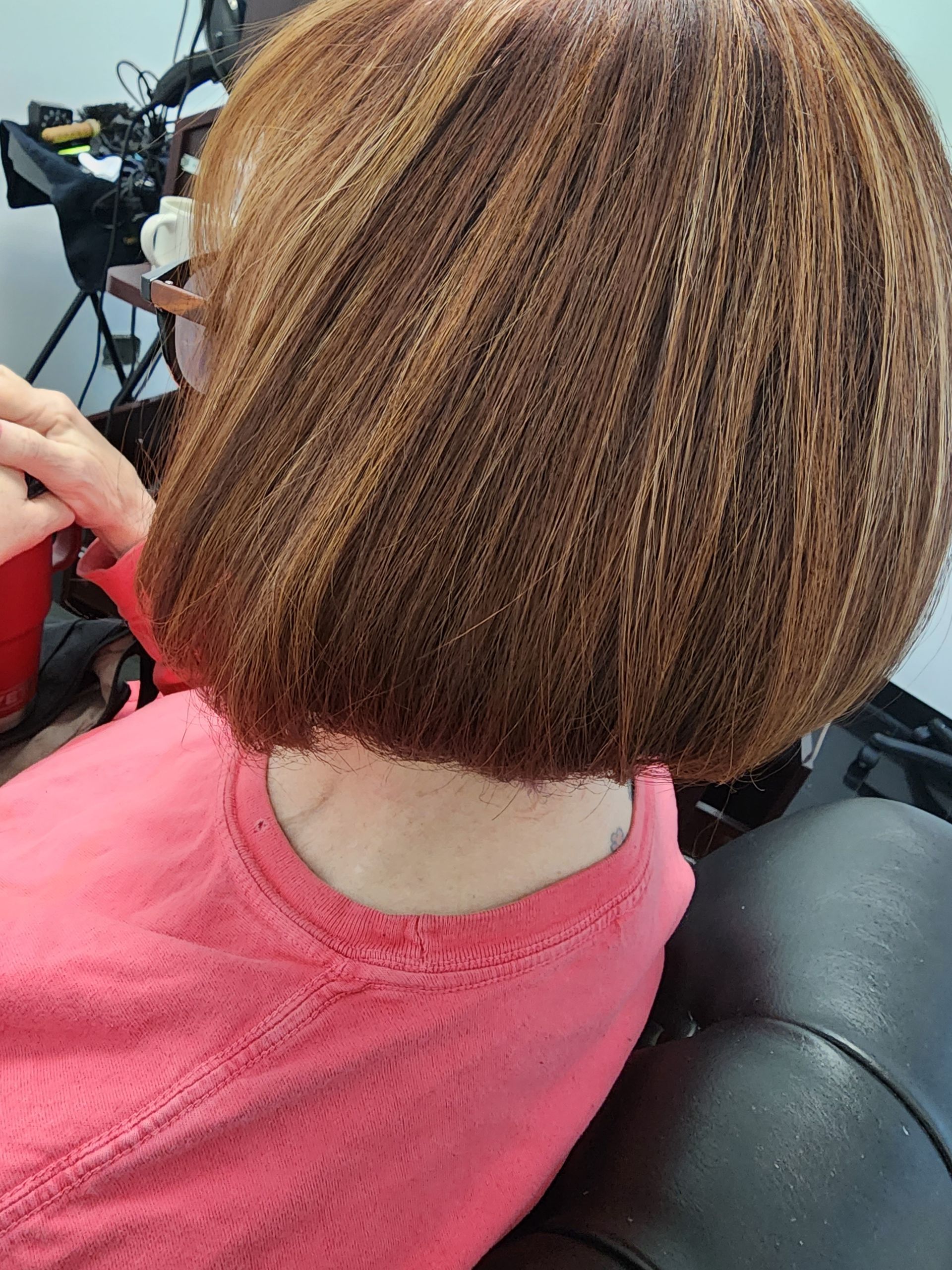 A woman is sitting in a chair with her hair cut into a bob.