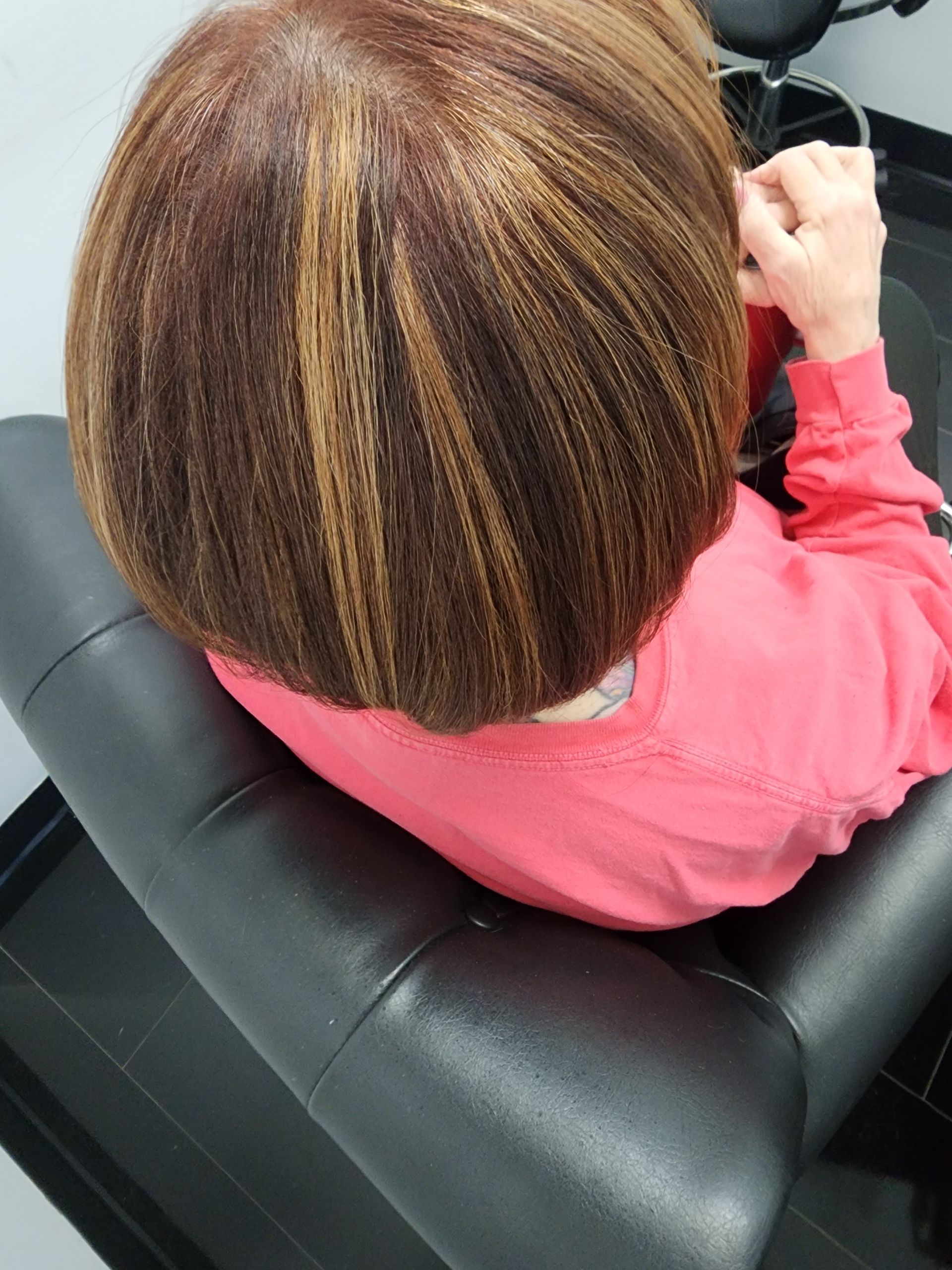 A woman in a pink shirt is sitting in a chair with her head down