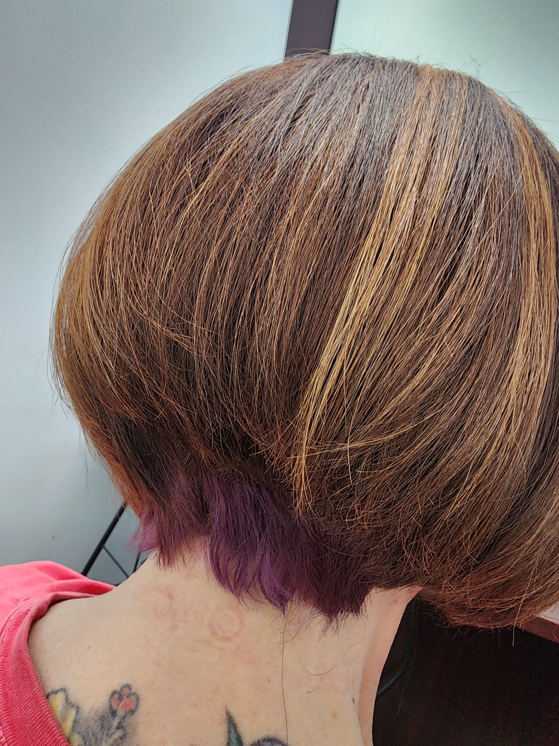 A woman with a tattoo on her back has a short haircut