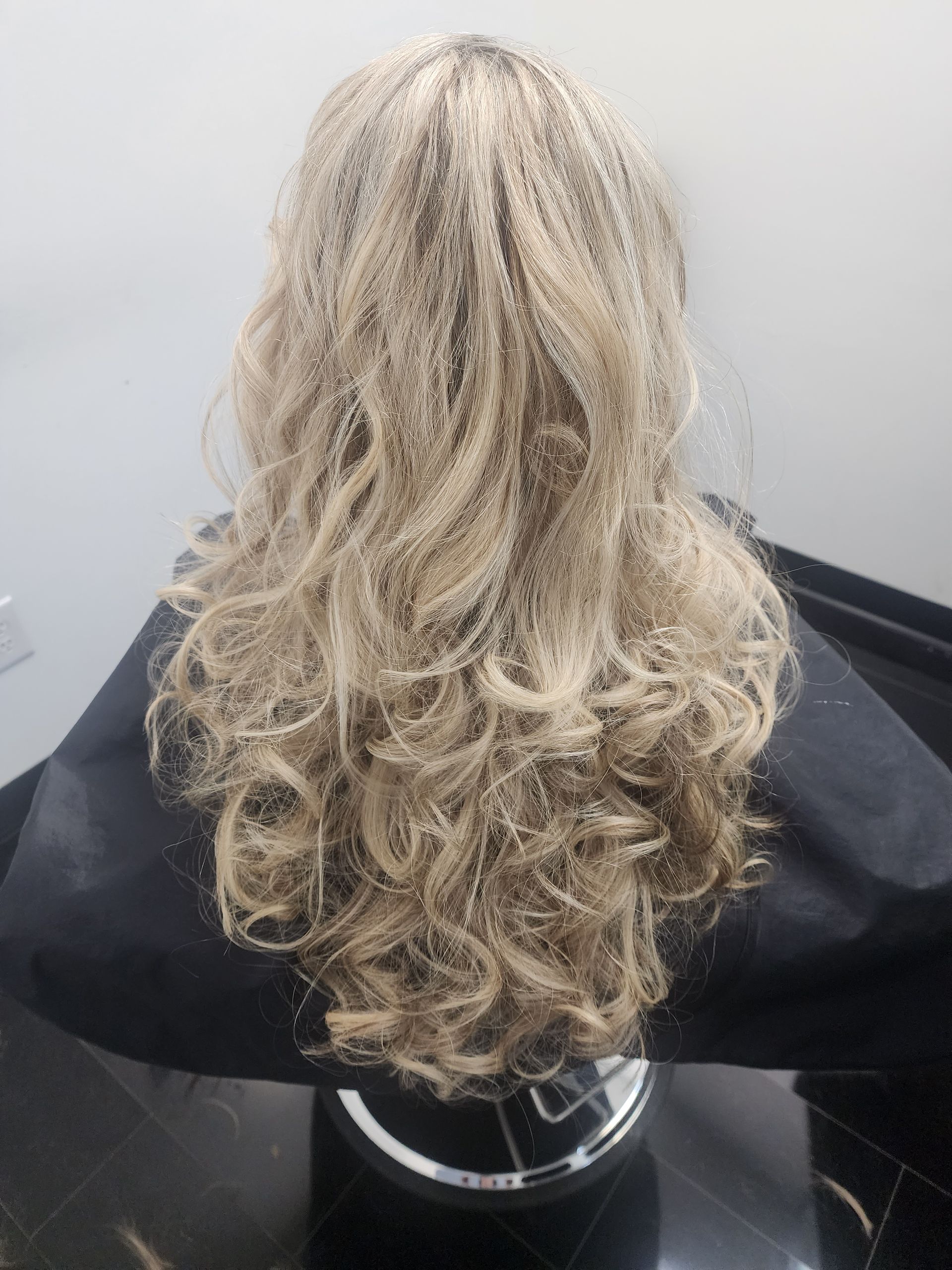The back of a blonde wig is shown on a mannequin.