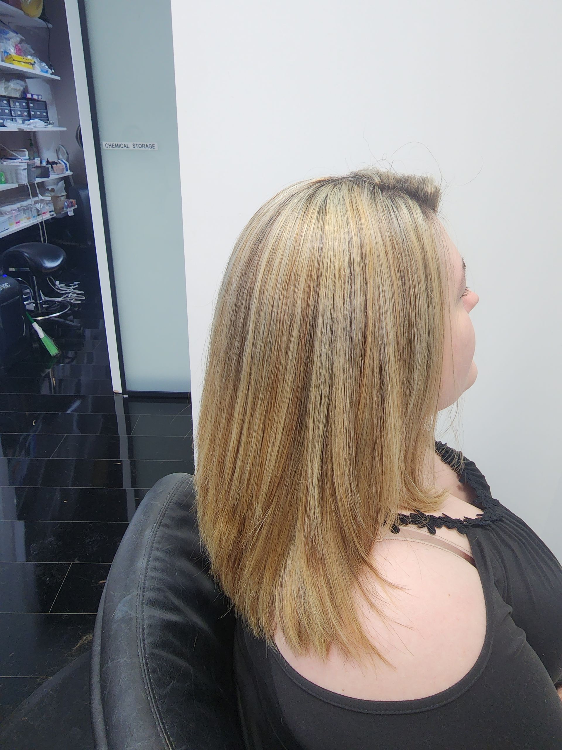 A woman with blonde hair is sitting in a chair in a room.