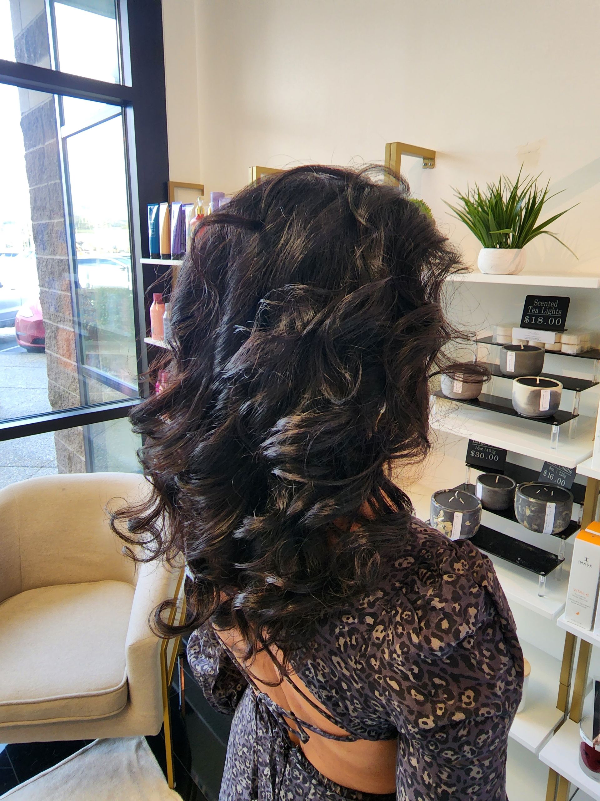 A woman with curly hair is sitting in a chair in a salon.