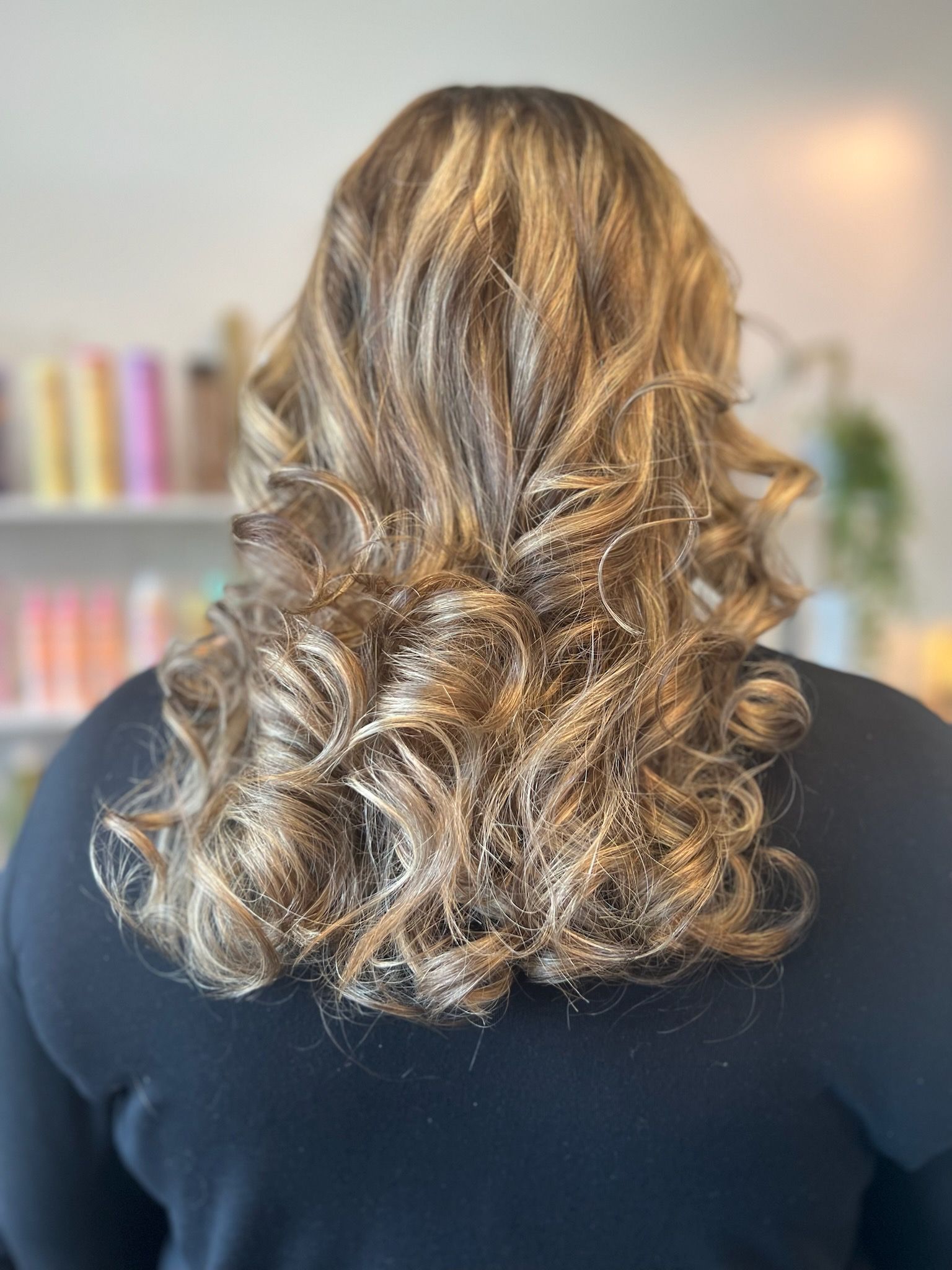A woman with long curly hair is wearing a black shirt.