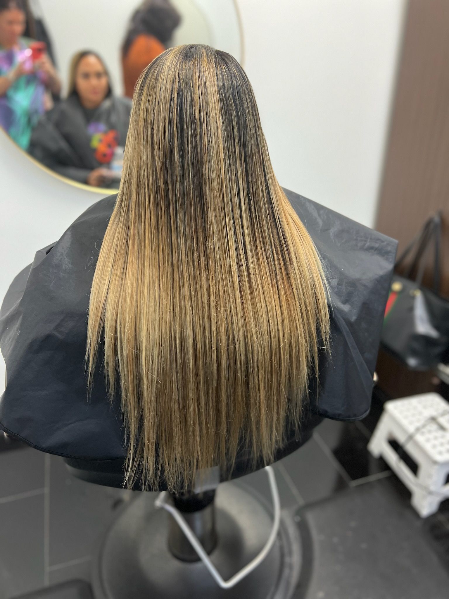 A woman 's hair is sitting on a chair in front of a mirror.
