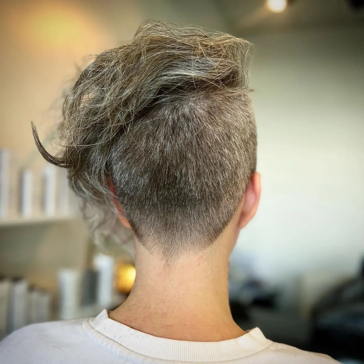 The back of a woman 's head with gray hair and a shaved head.