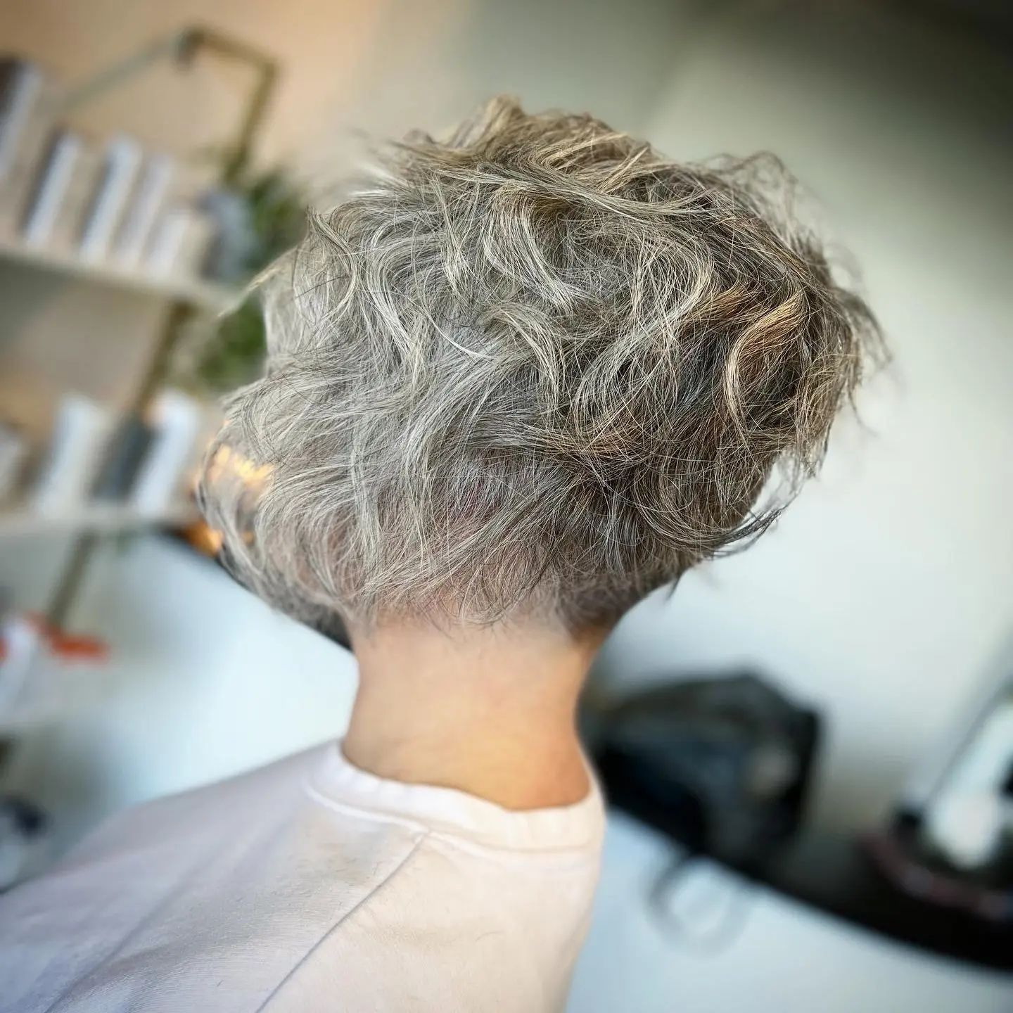 A woman with gray hair is sitting in a chair with her hair in a bun.