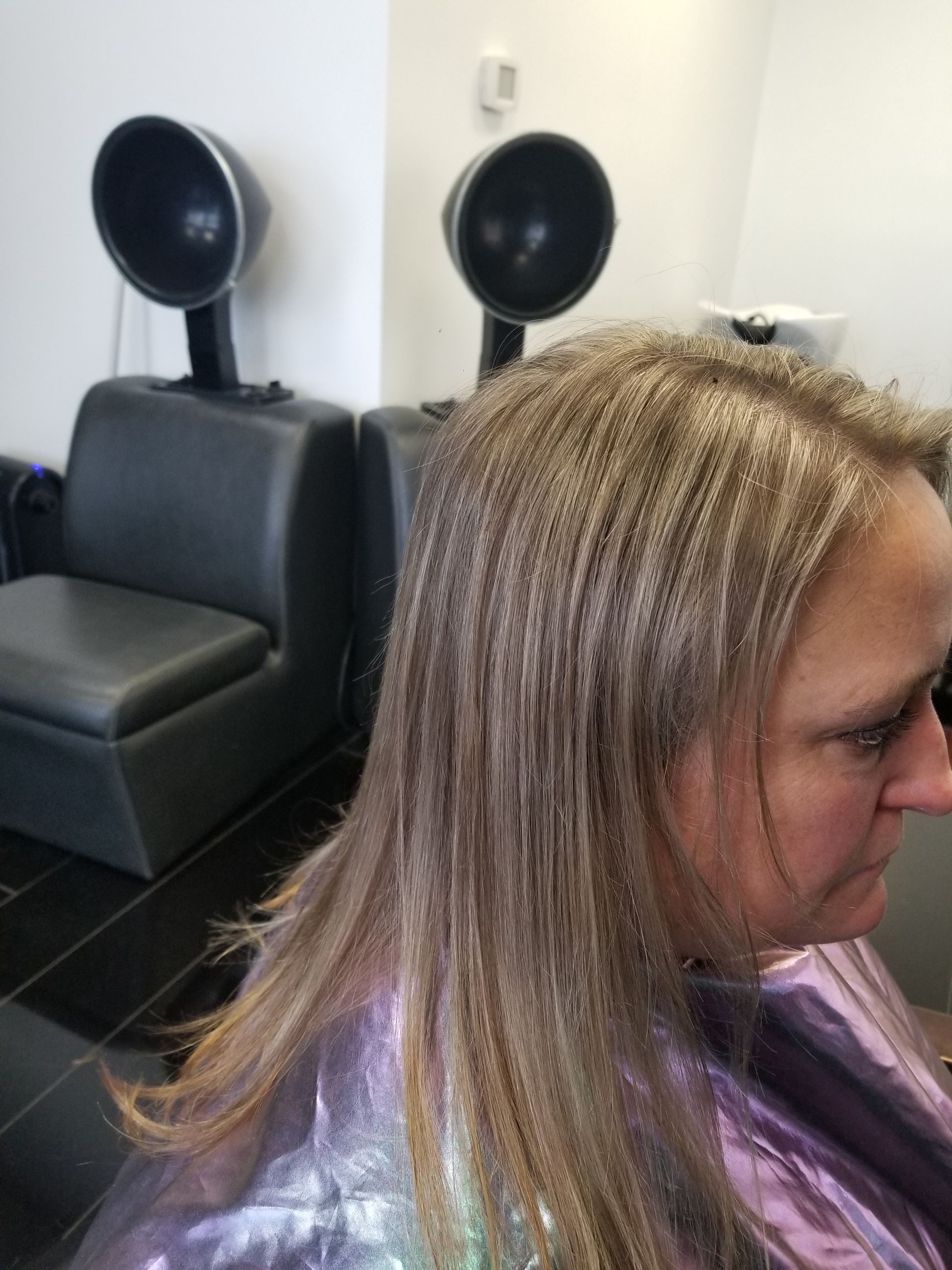 A woman is getting her hair dyed in a salon