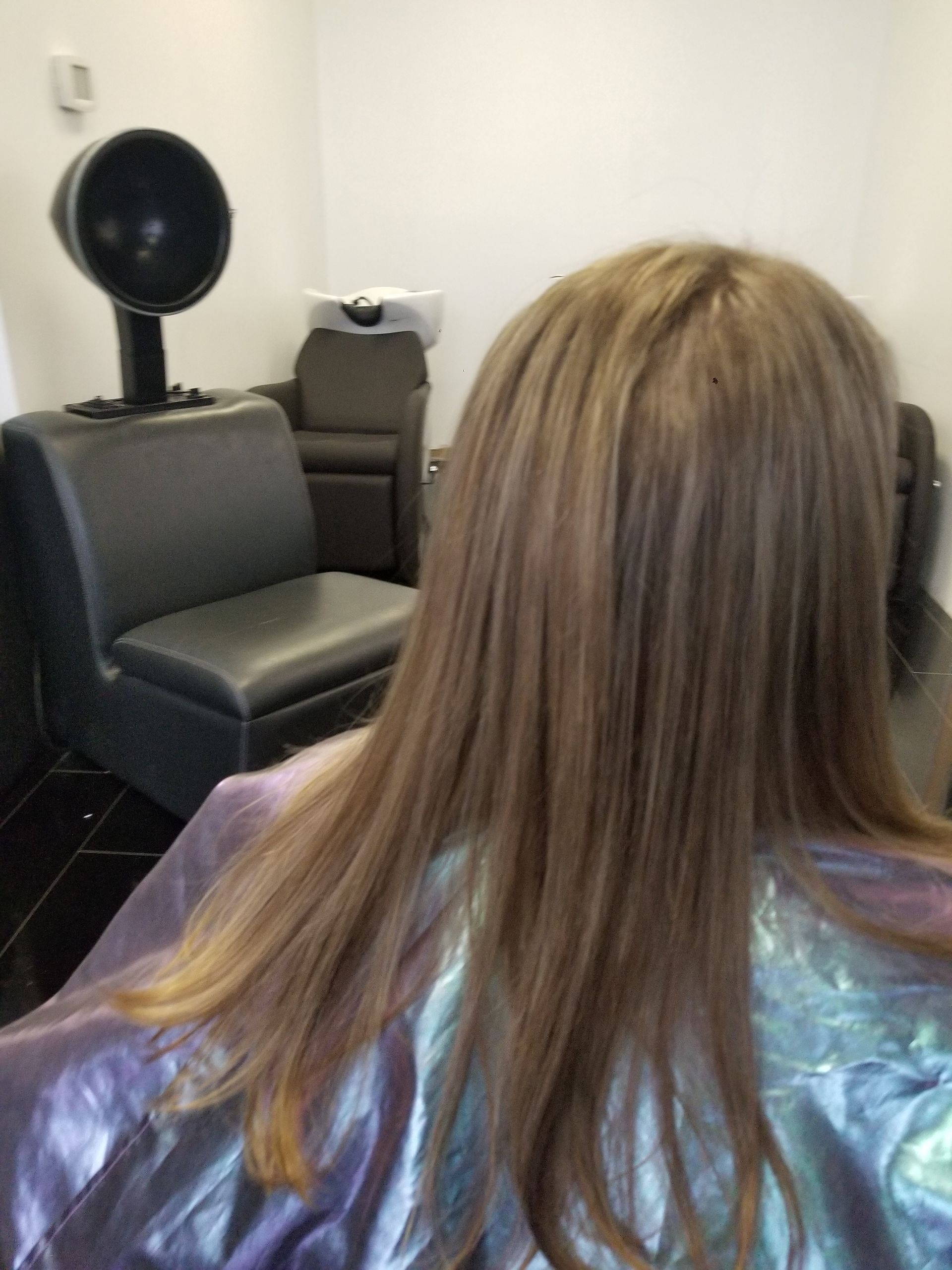 A woman with long hair is sitting in a chair in a salon.