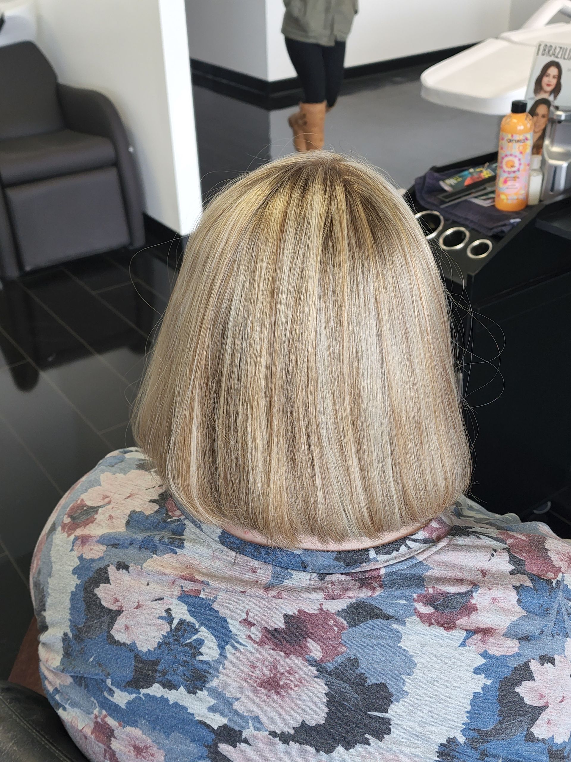 A woman with blonde hair is sitting in a chair in a salon.