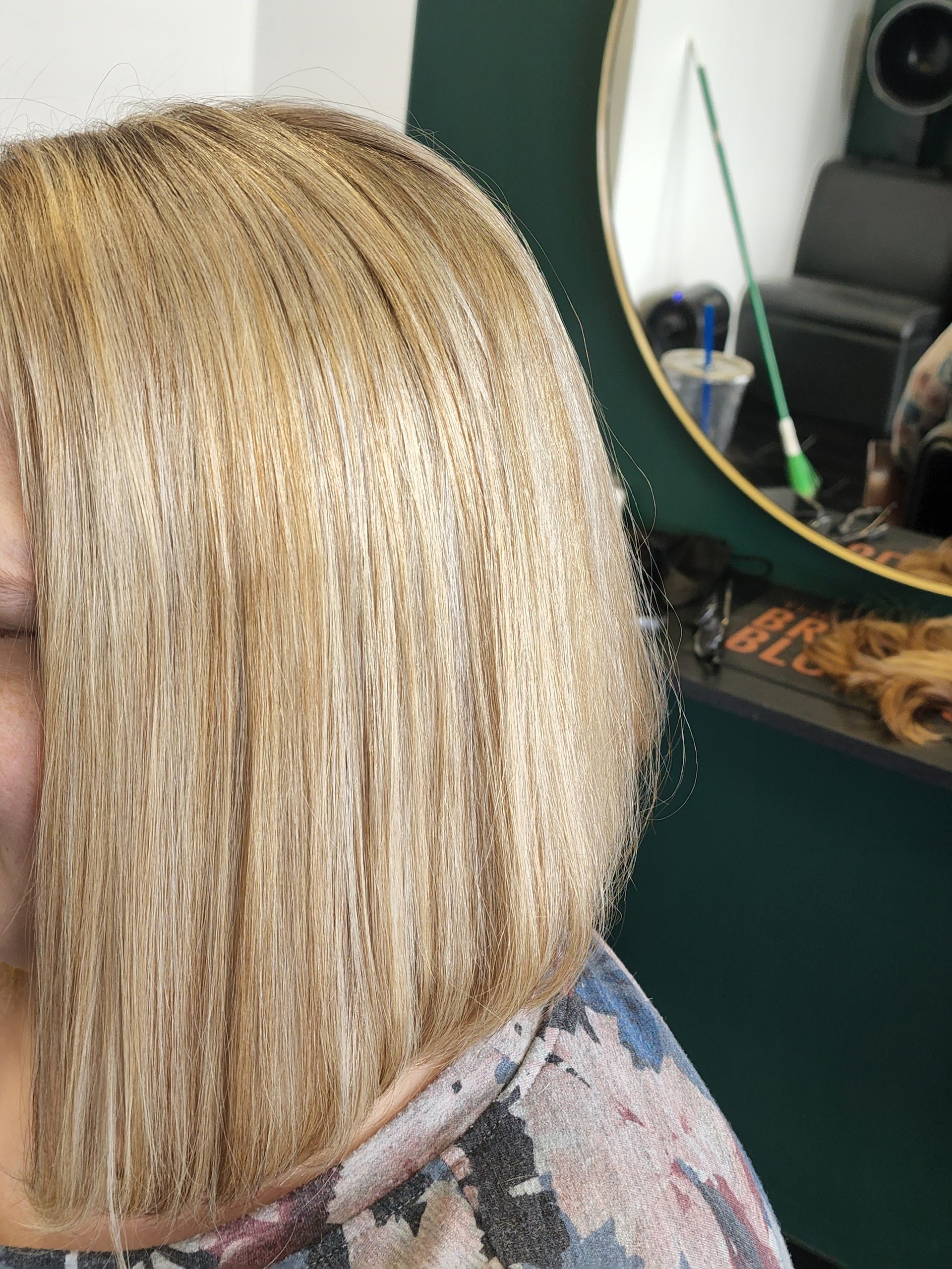A woman with blonde hair is sitting in front of a mirror.
