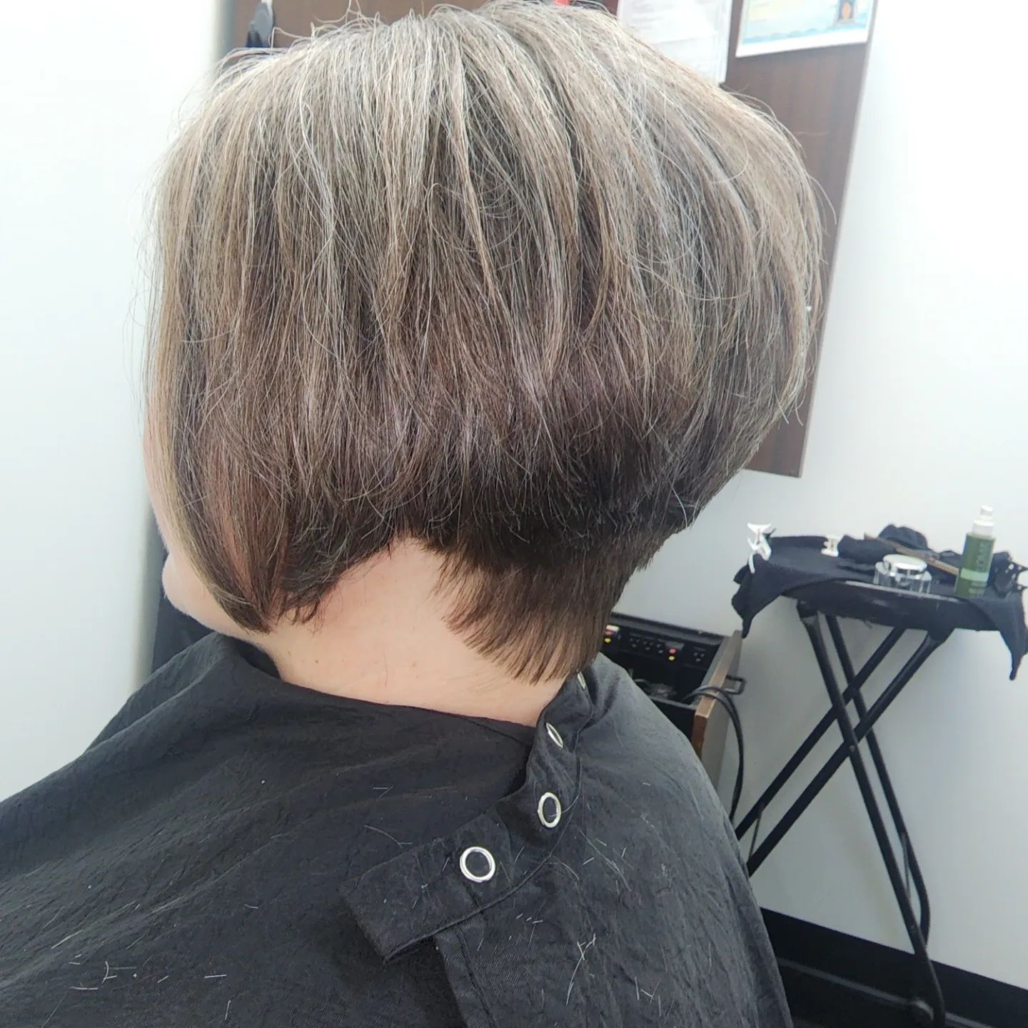 A woman is getting her hair cut in a salon