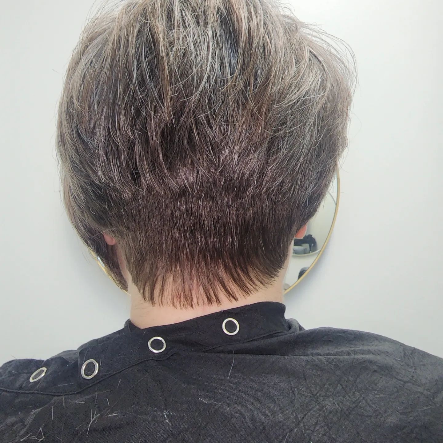 The back of a person 's head with a mirror in the background