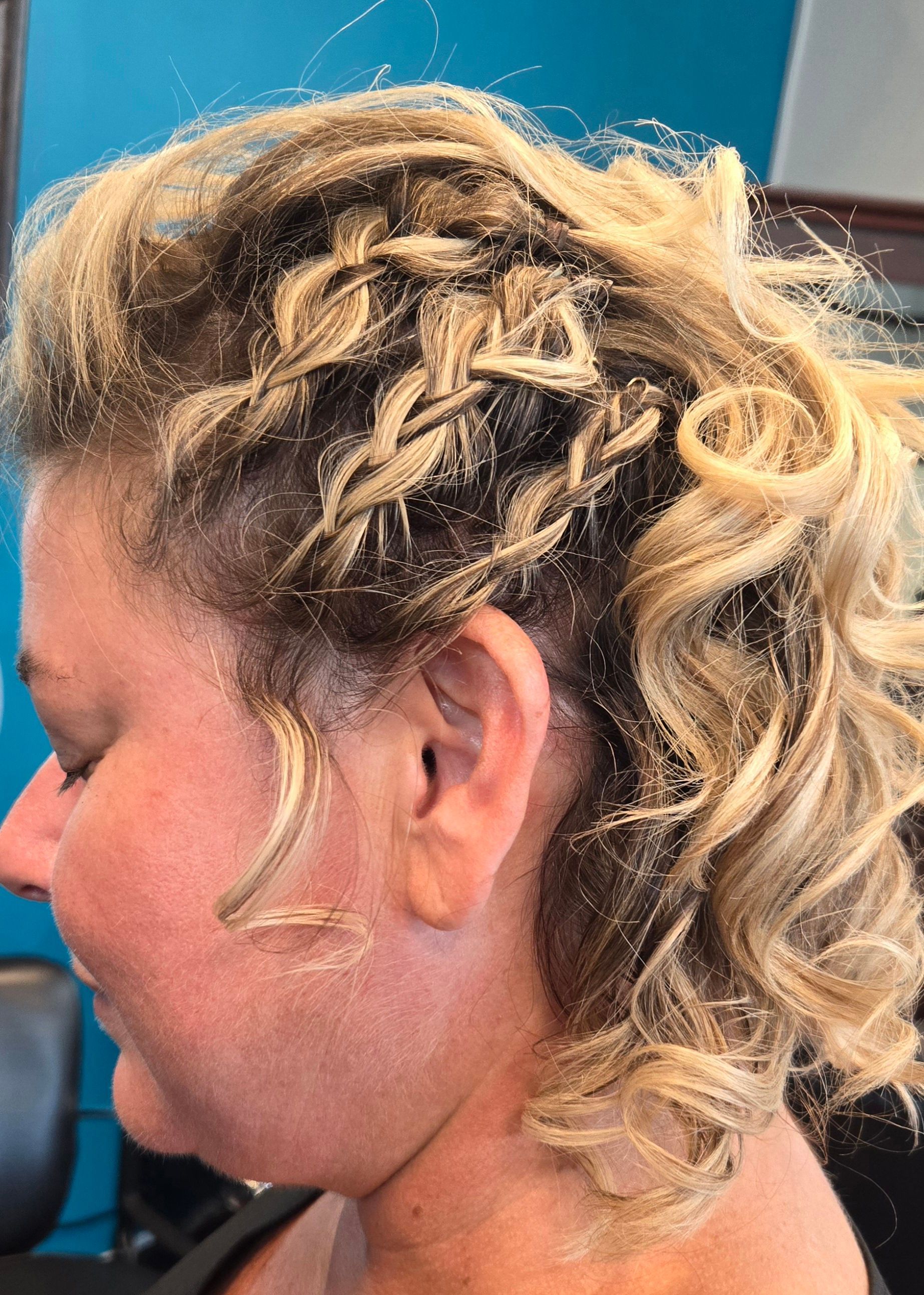 A woman with blonde hair is wearing a braided hairstyle.