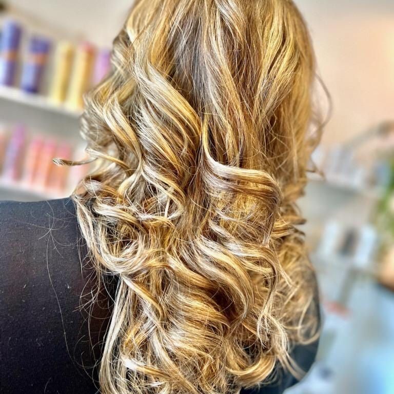 A woman with long blonde curly hair is wearing a black shirt