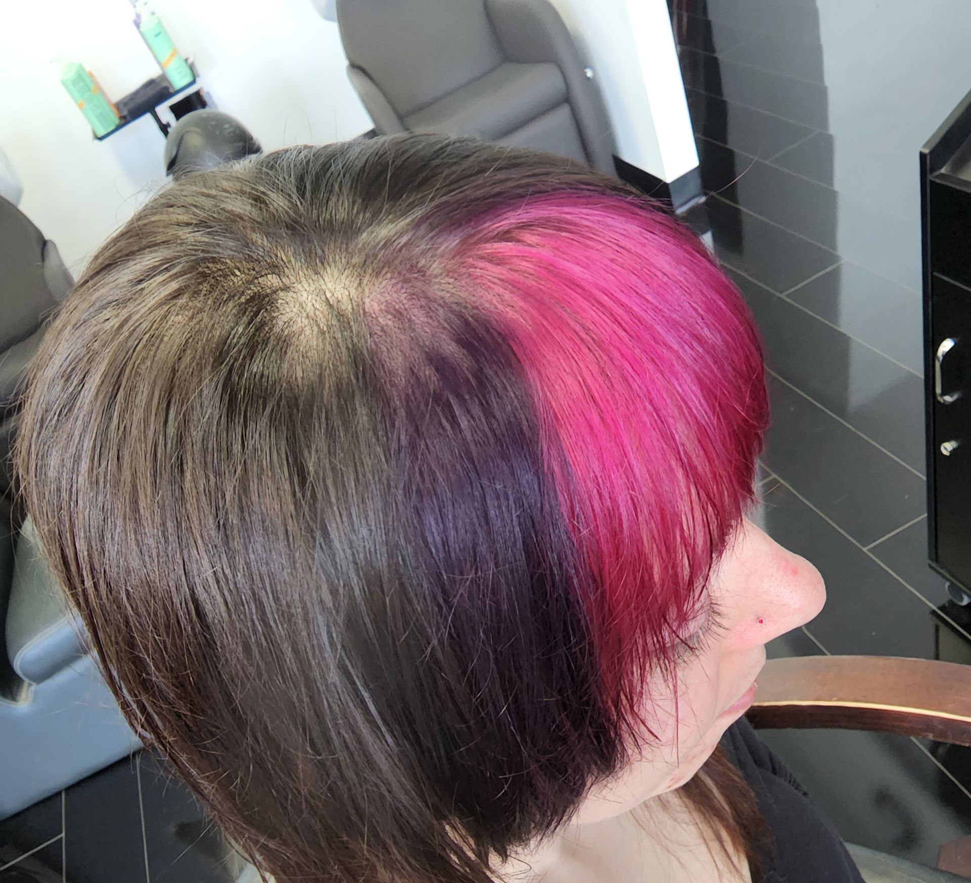 A woman with purple and pink hair is sitting in a chair