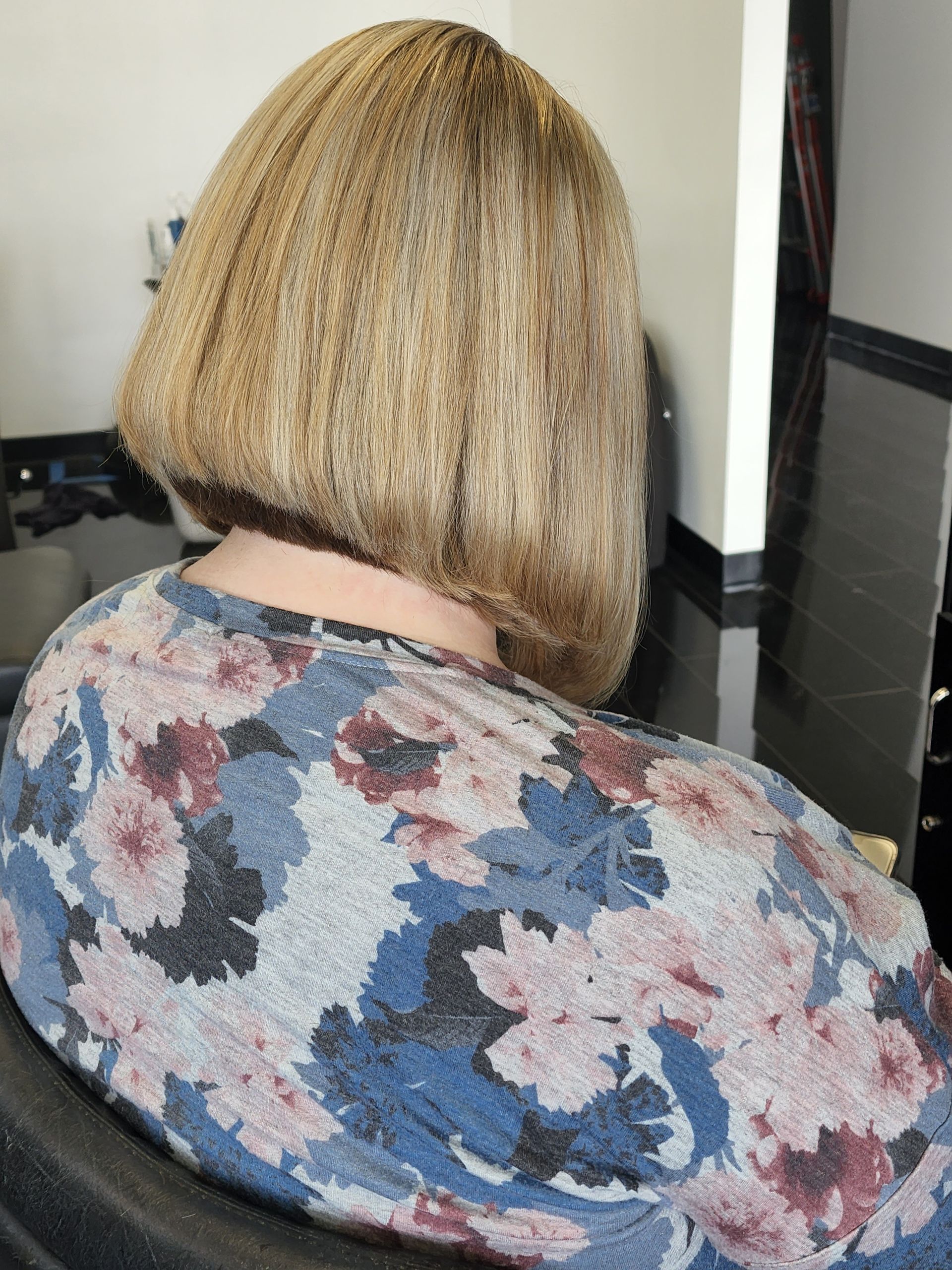A woman with short blonde hair is wearing a floral shirt.