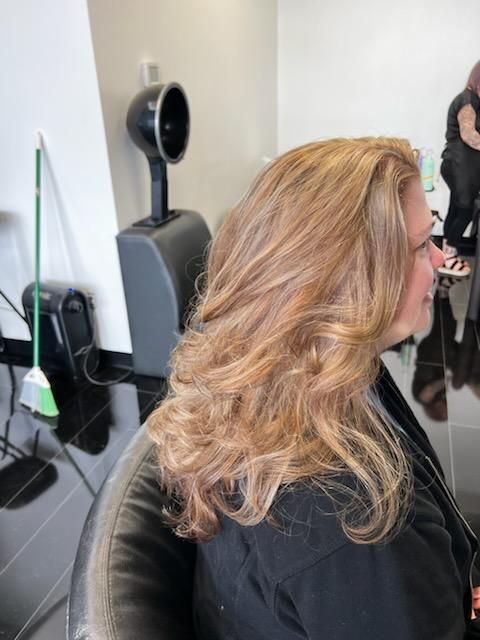A woman with long blonde hair is sitting in a chair in a salon.