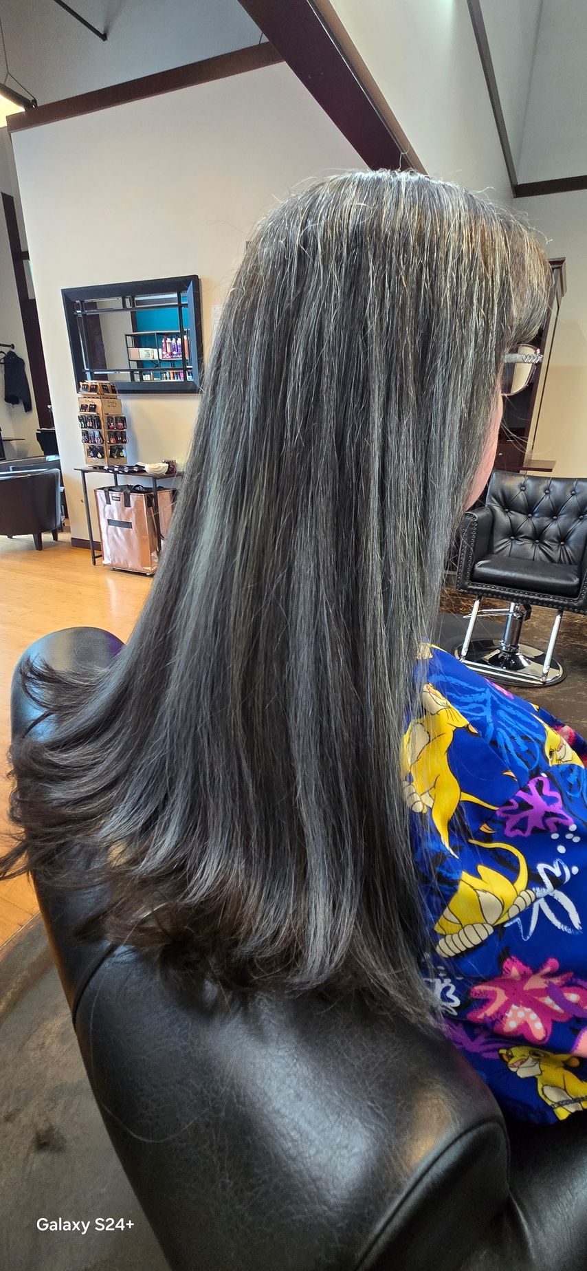 A woman is sitting in a chair with her hair in a salon.