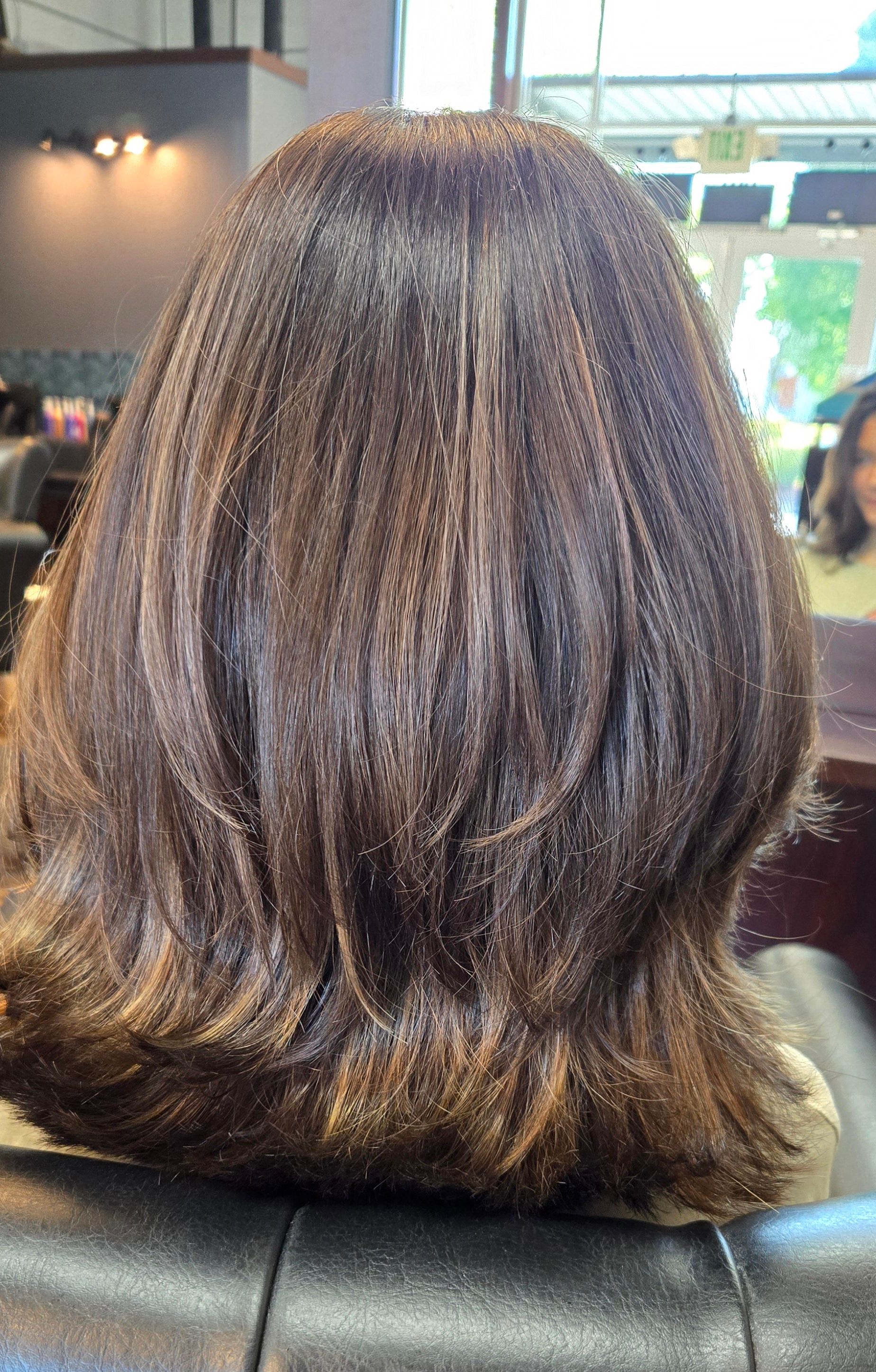 The back of a woman 's hair is shown in a salon.