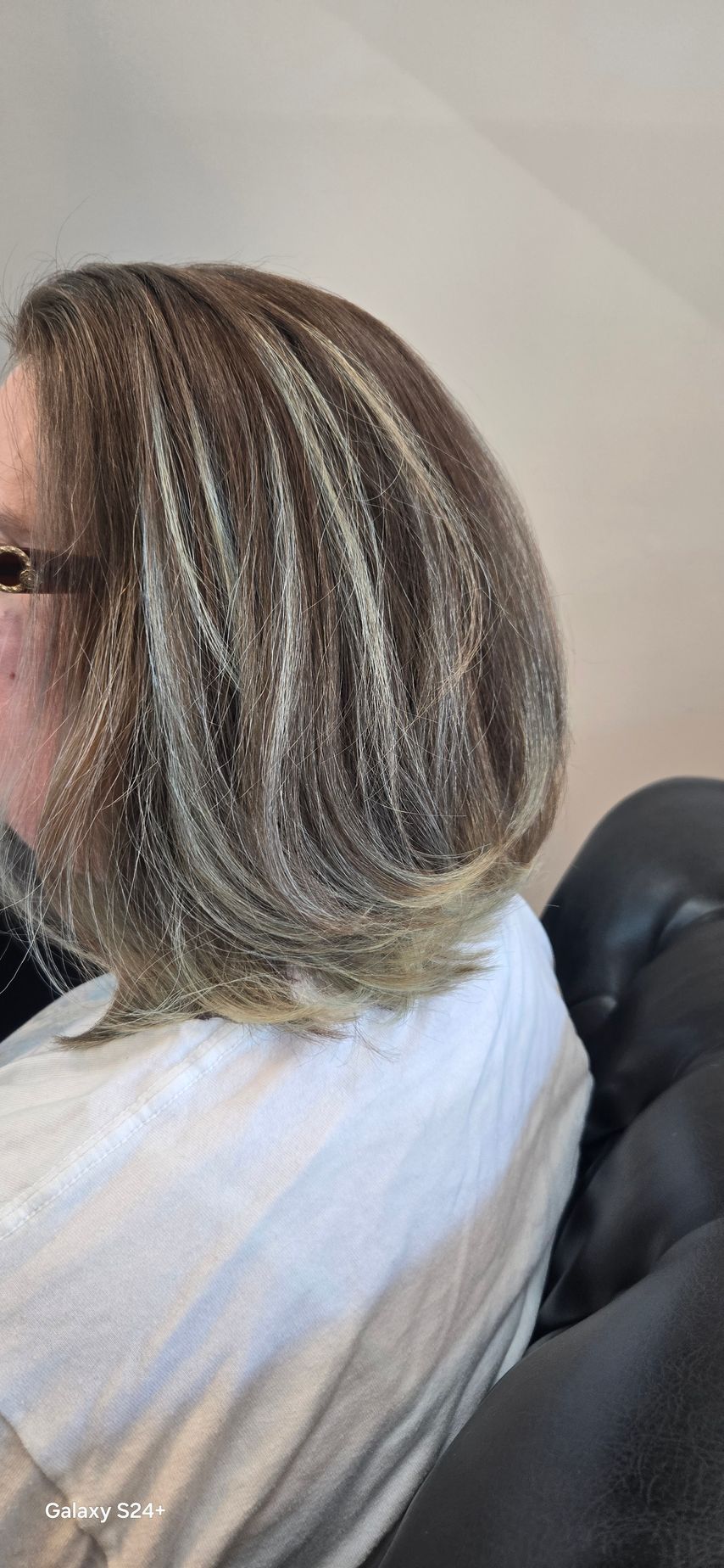 A woman with short hair and glasses is sitting in a chair.