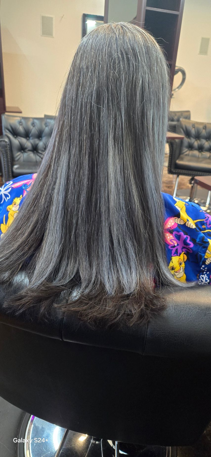 A woman is sitting in a chair with her hair in a salon.