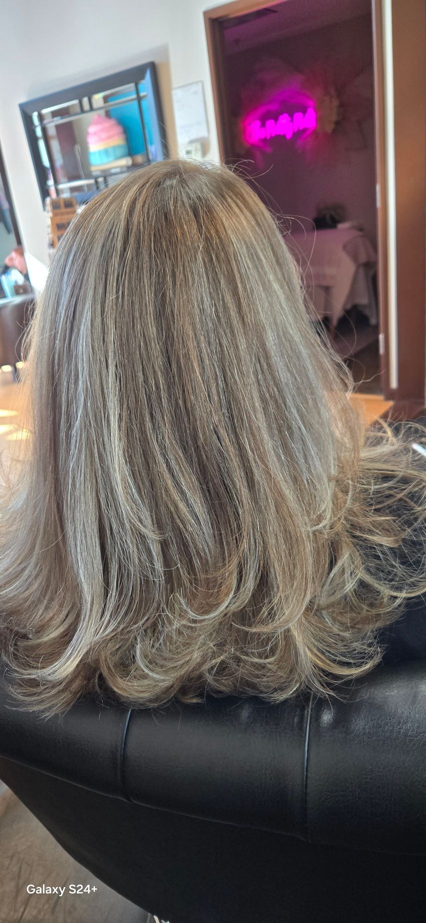 A woman with blonde hair is sitting on a couch in a living room.