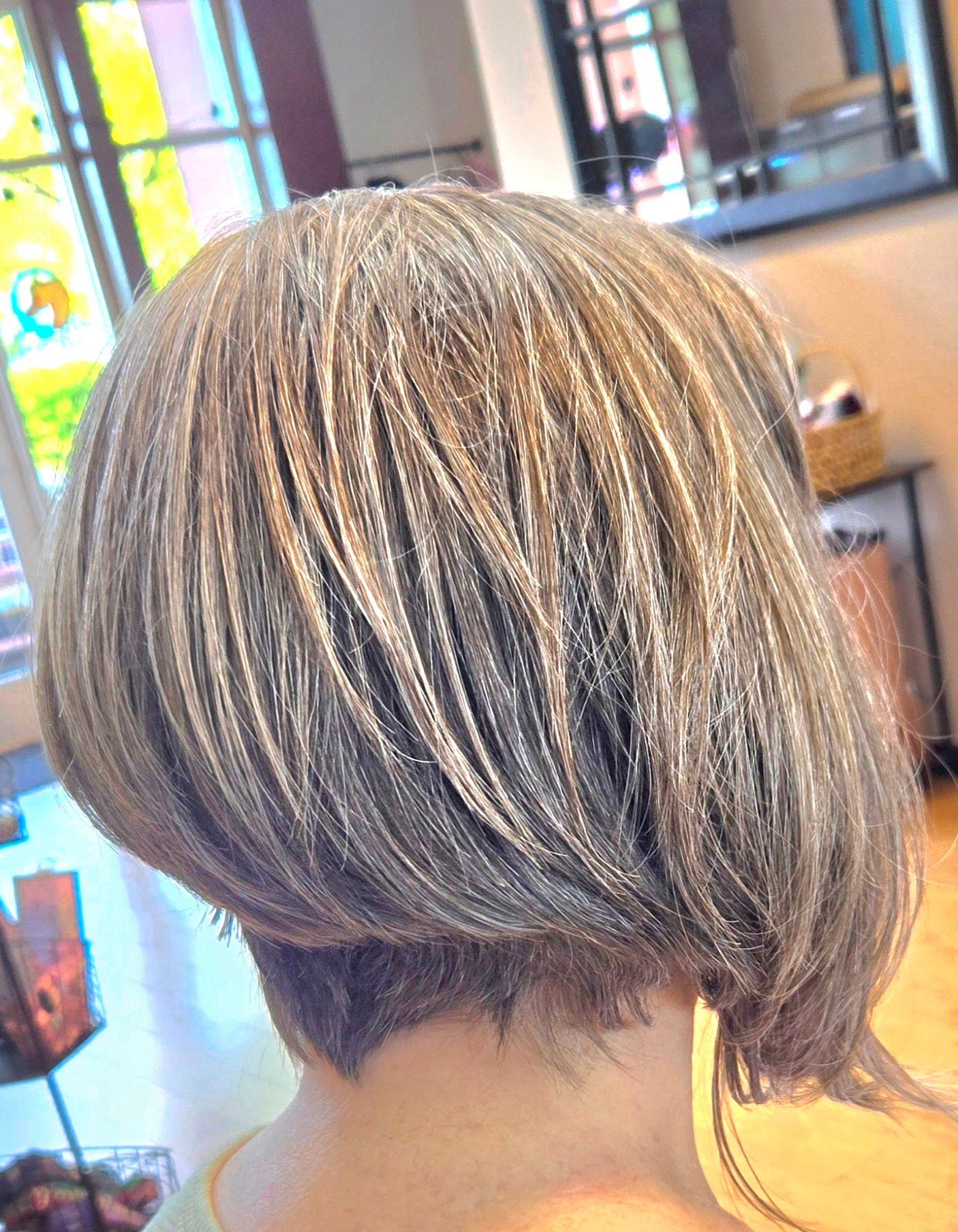 A woman is getting her hair cut in a salon.