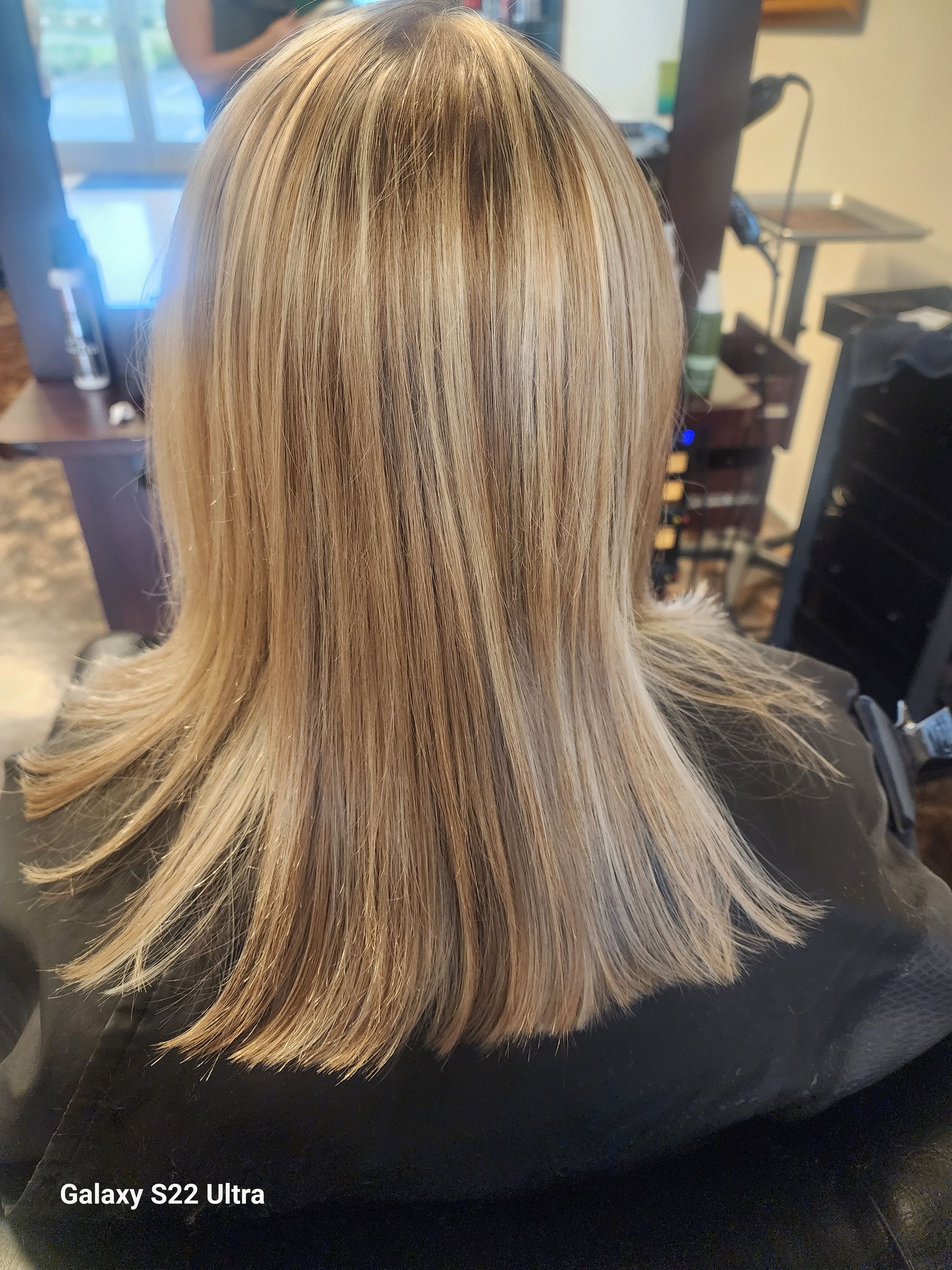 A woman with blonde hair is sitting in a chair in a salon.