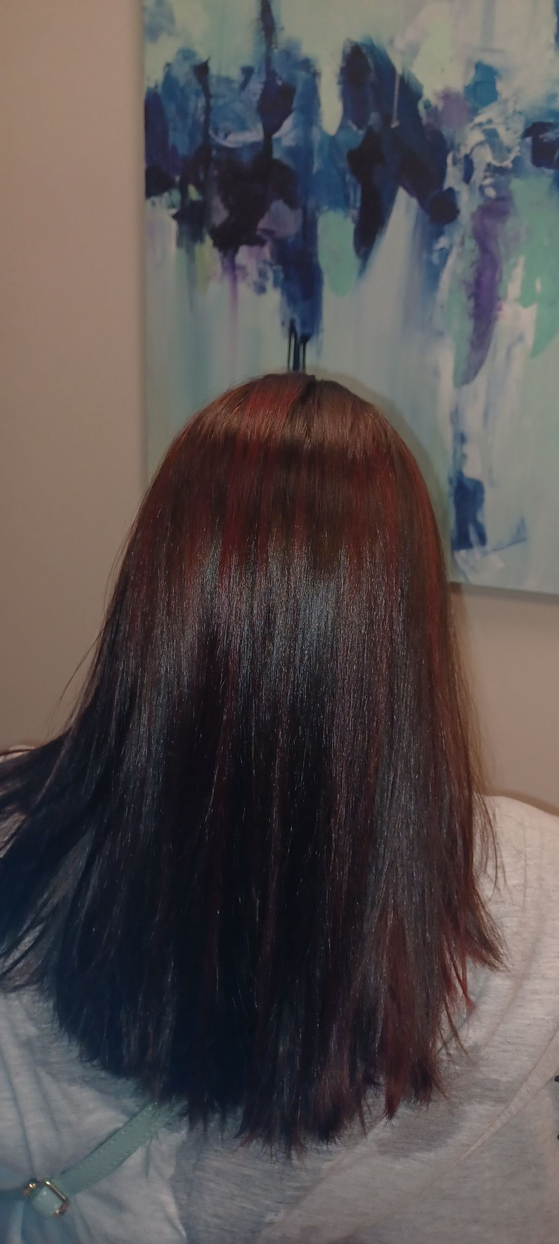 A close up of a person 's hair in front of a painting.