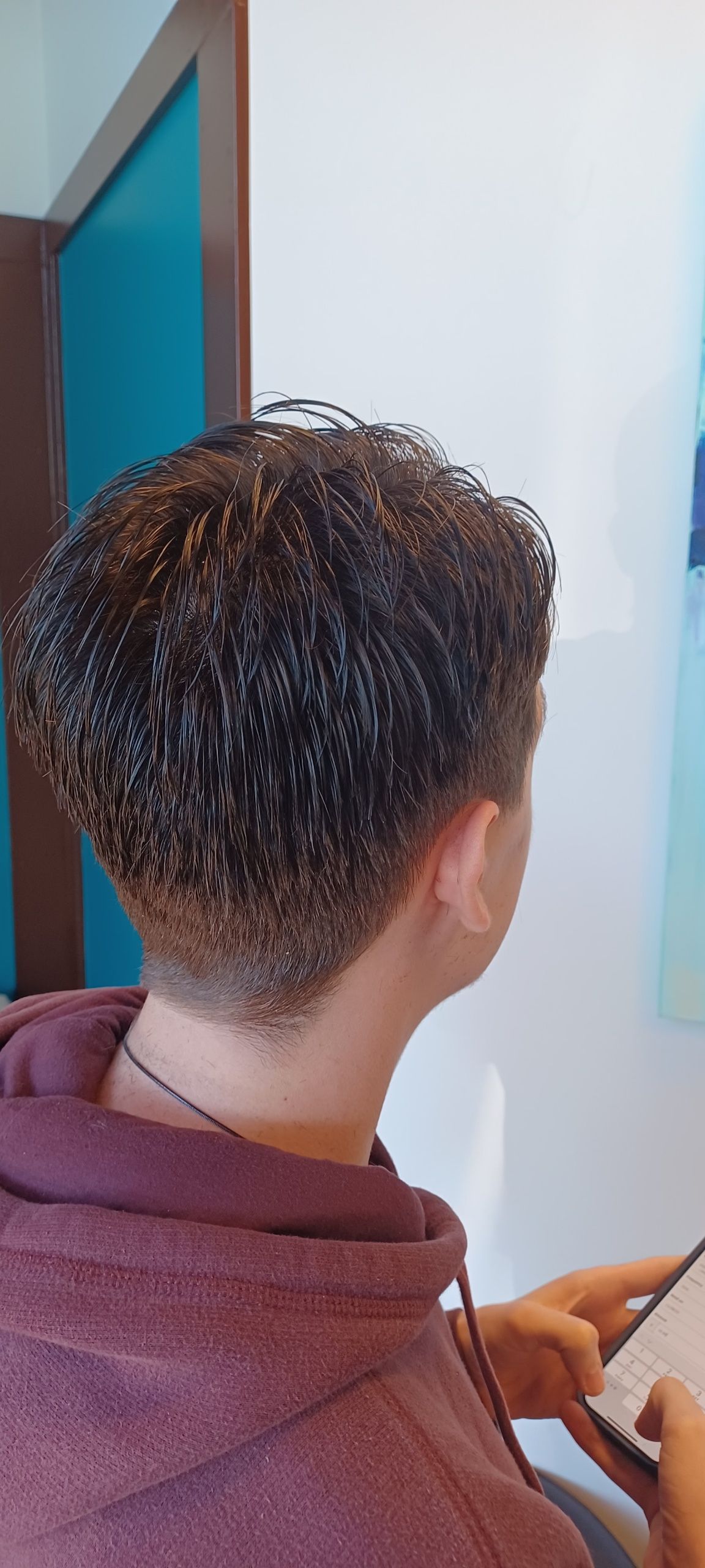 A man with curly hair is sitting in a chair looking at a tablet.