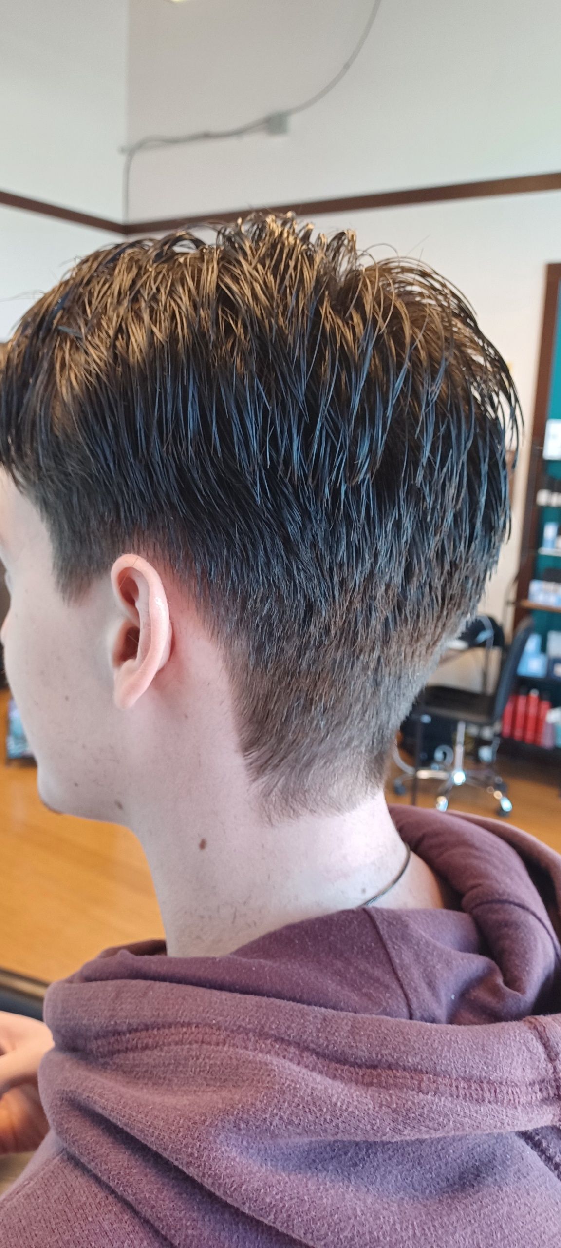 A young man is getting his hair cut in a salon.