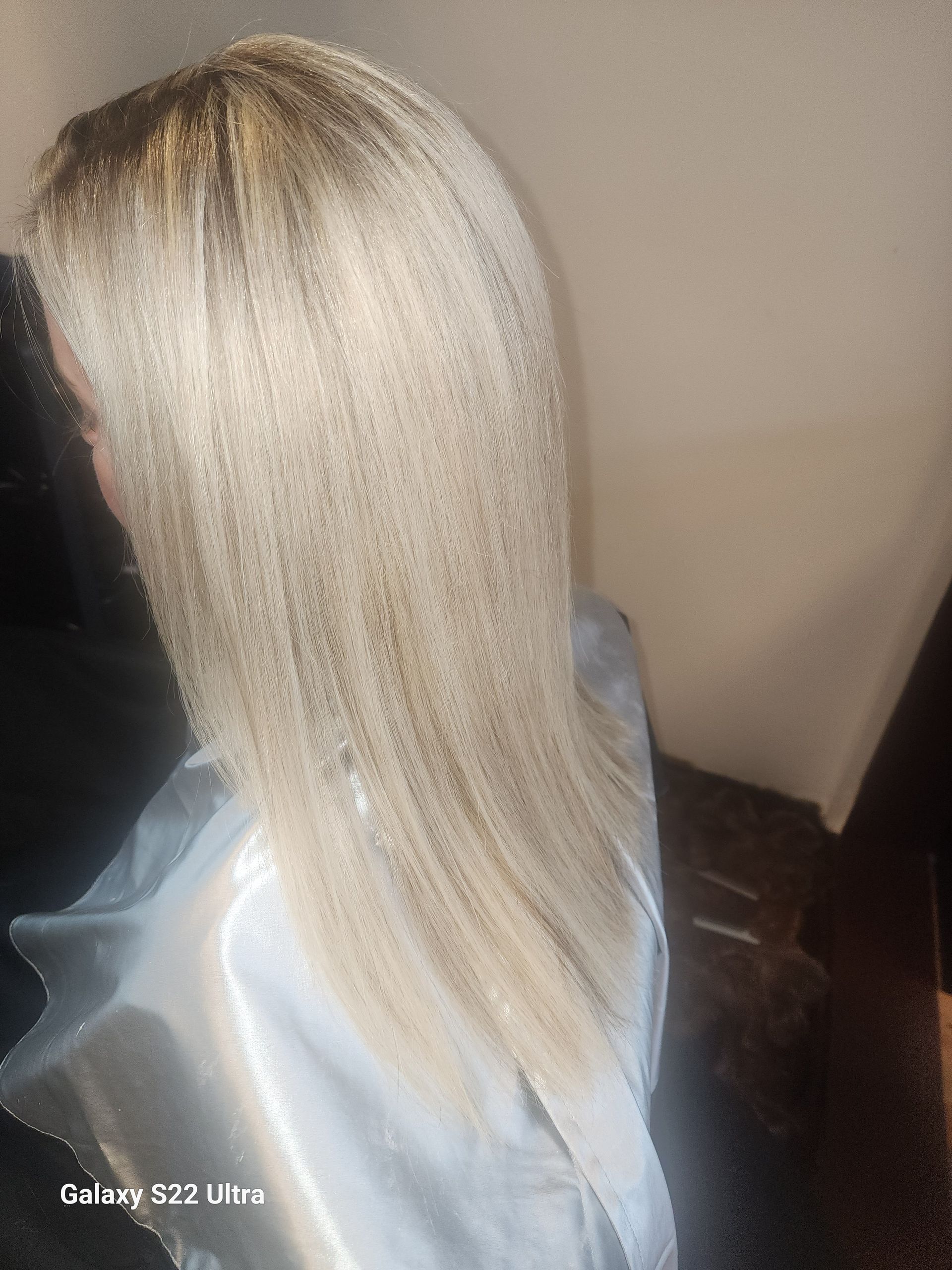 A woman with long blonde hair is sitting in a chair.