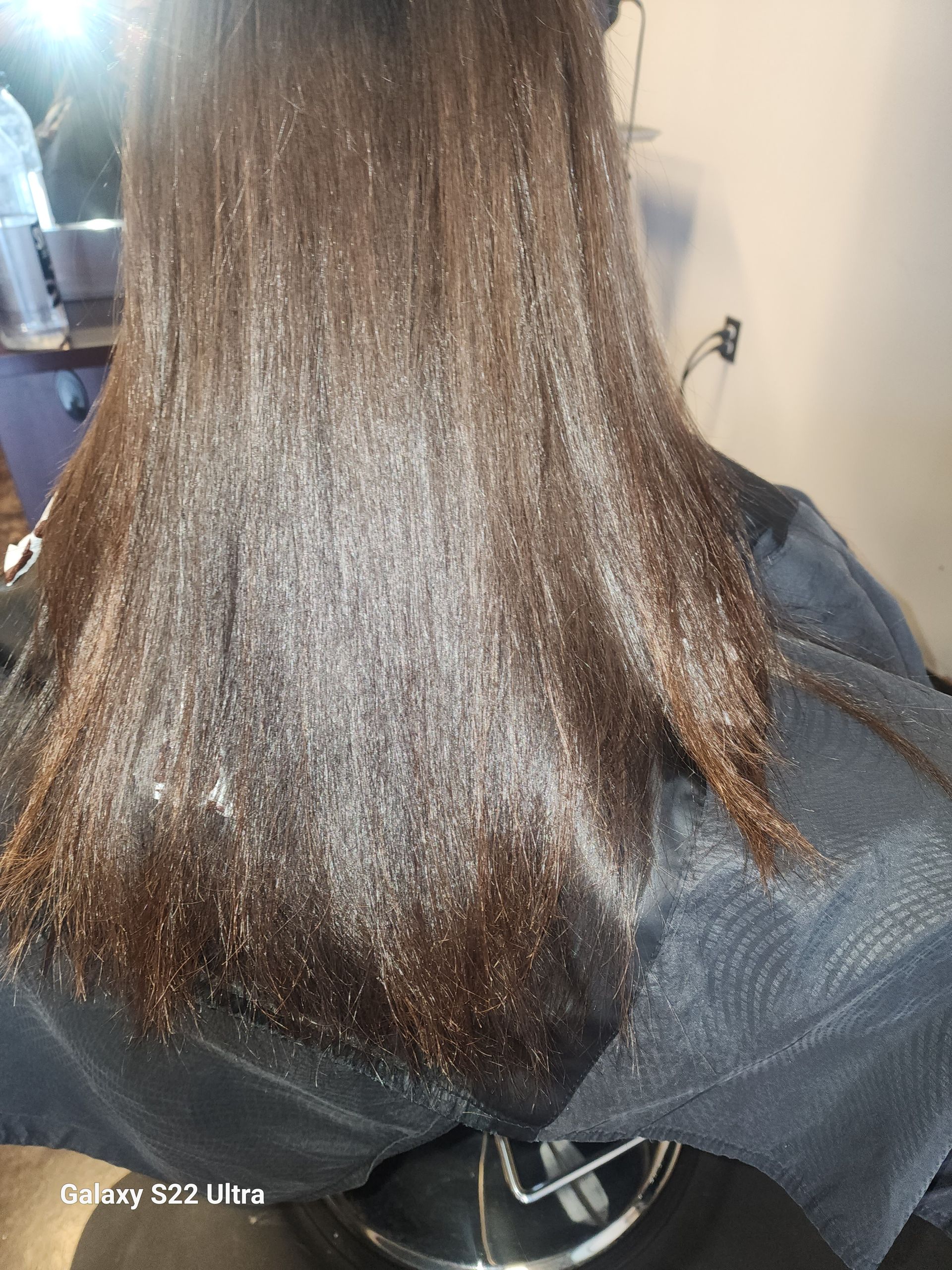 A woman is getting her hair straightened in a salon.