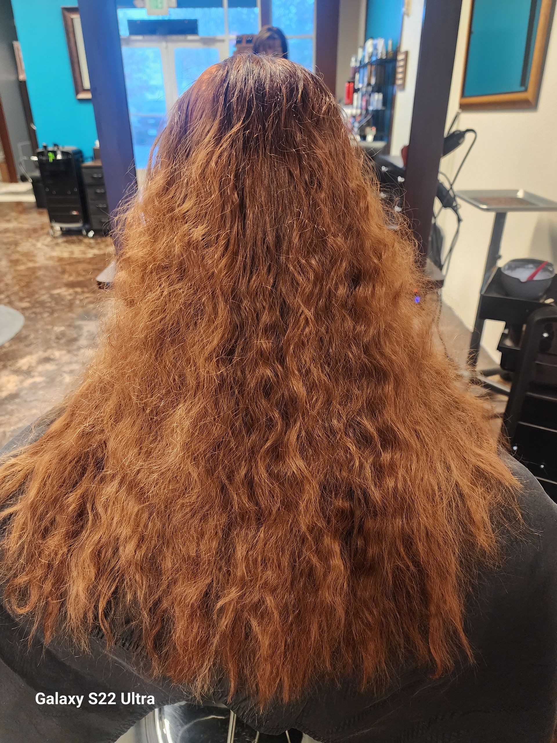 A woman with long hair is sitting in a chair in a salon.