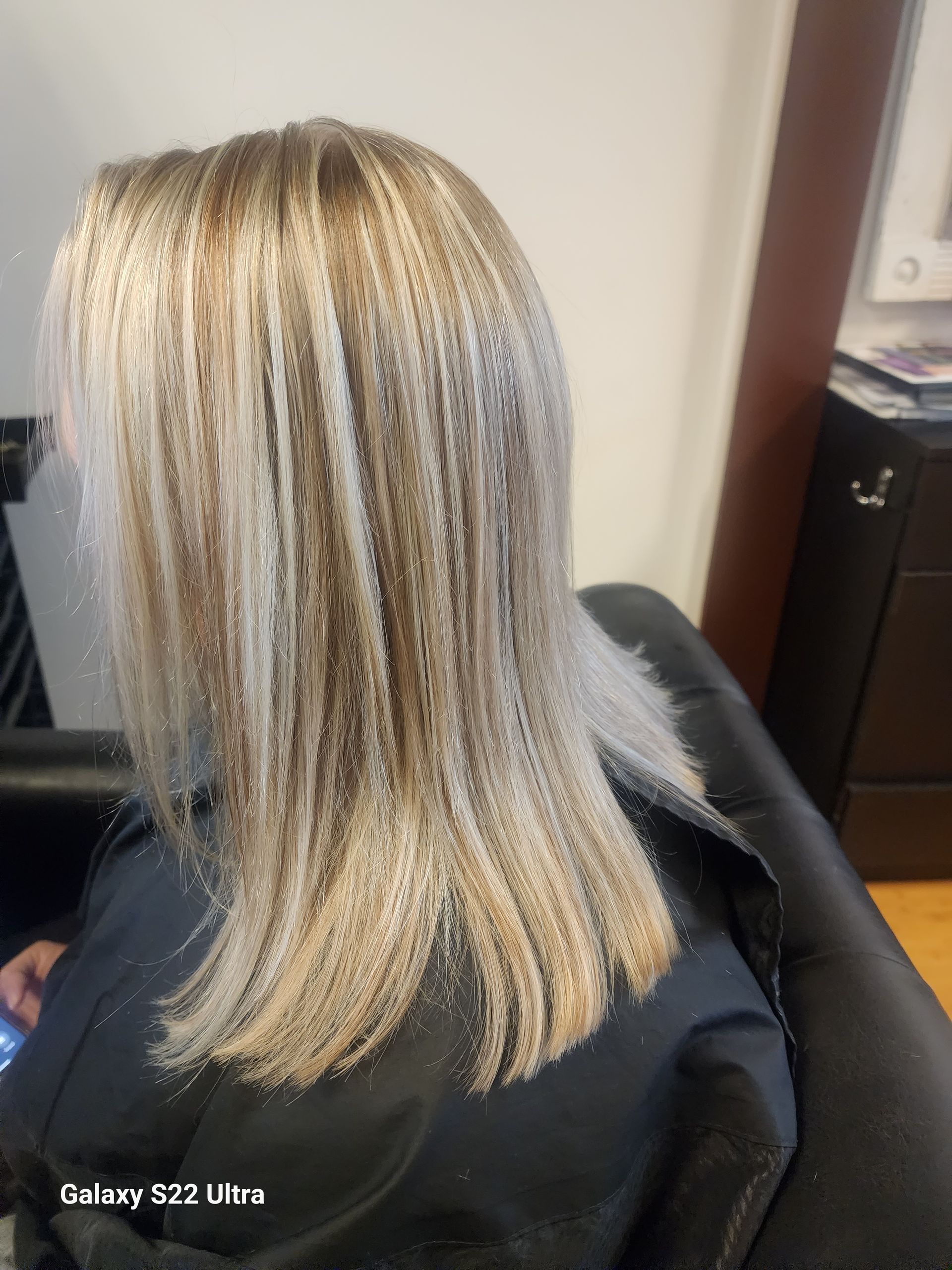 A woman with long blonde hair is sitting in a chair.
