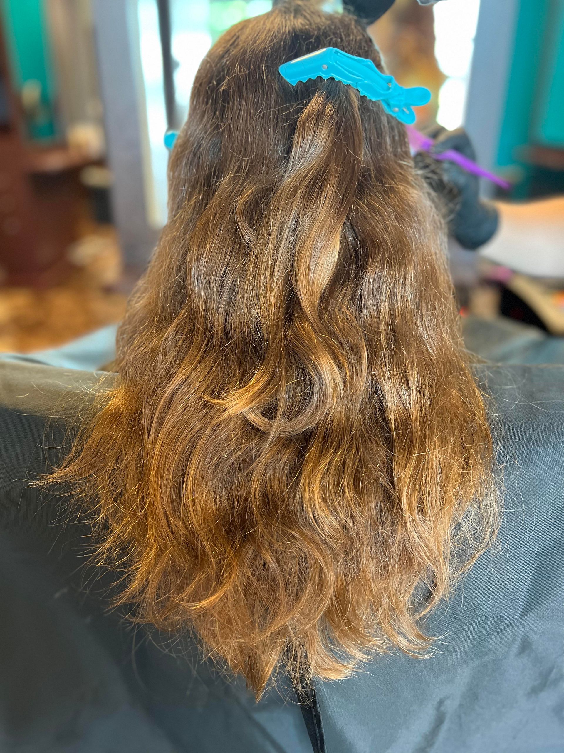 A woman is sitting in a chair with her hair in a ponytail.