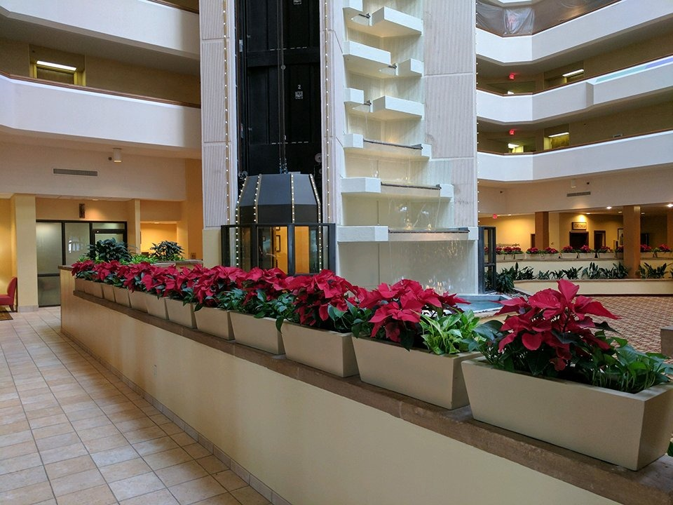 Indoor atrium with tiered balconies and a planter of red poinsettias along a tiled walkway