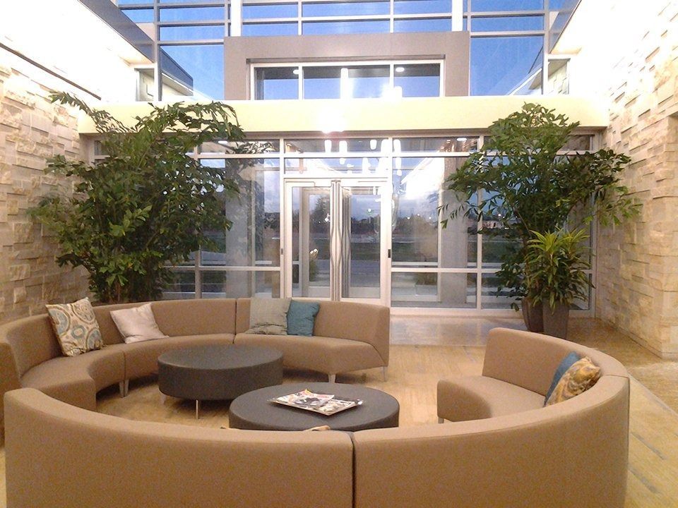 Modern lobby seating area with a circular sofa, round table, and tall windows.