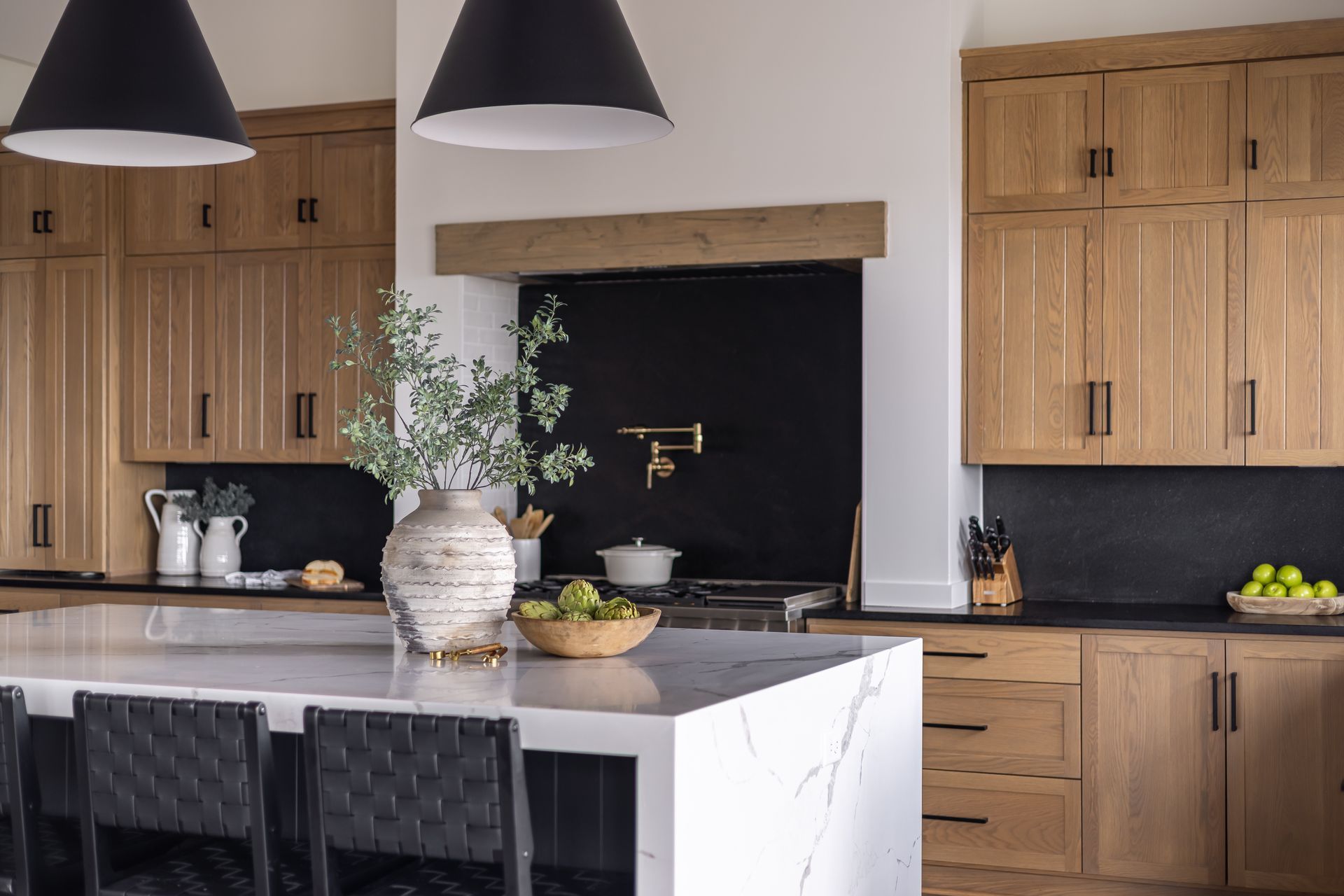 Modern kitchen with wood cabinets, black countertops, marble island, and pendant lights