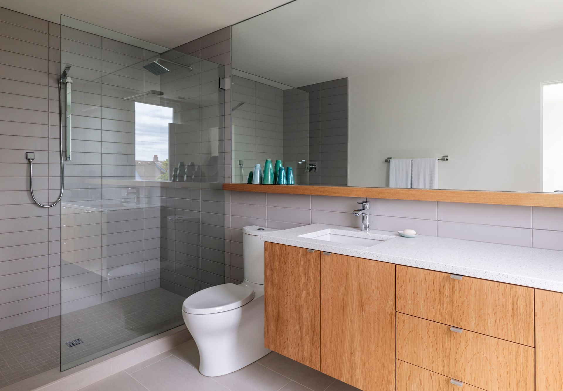 Modern bathroom with glass shower, white toilet, and wood vanity with sink