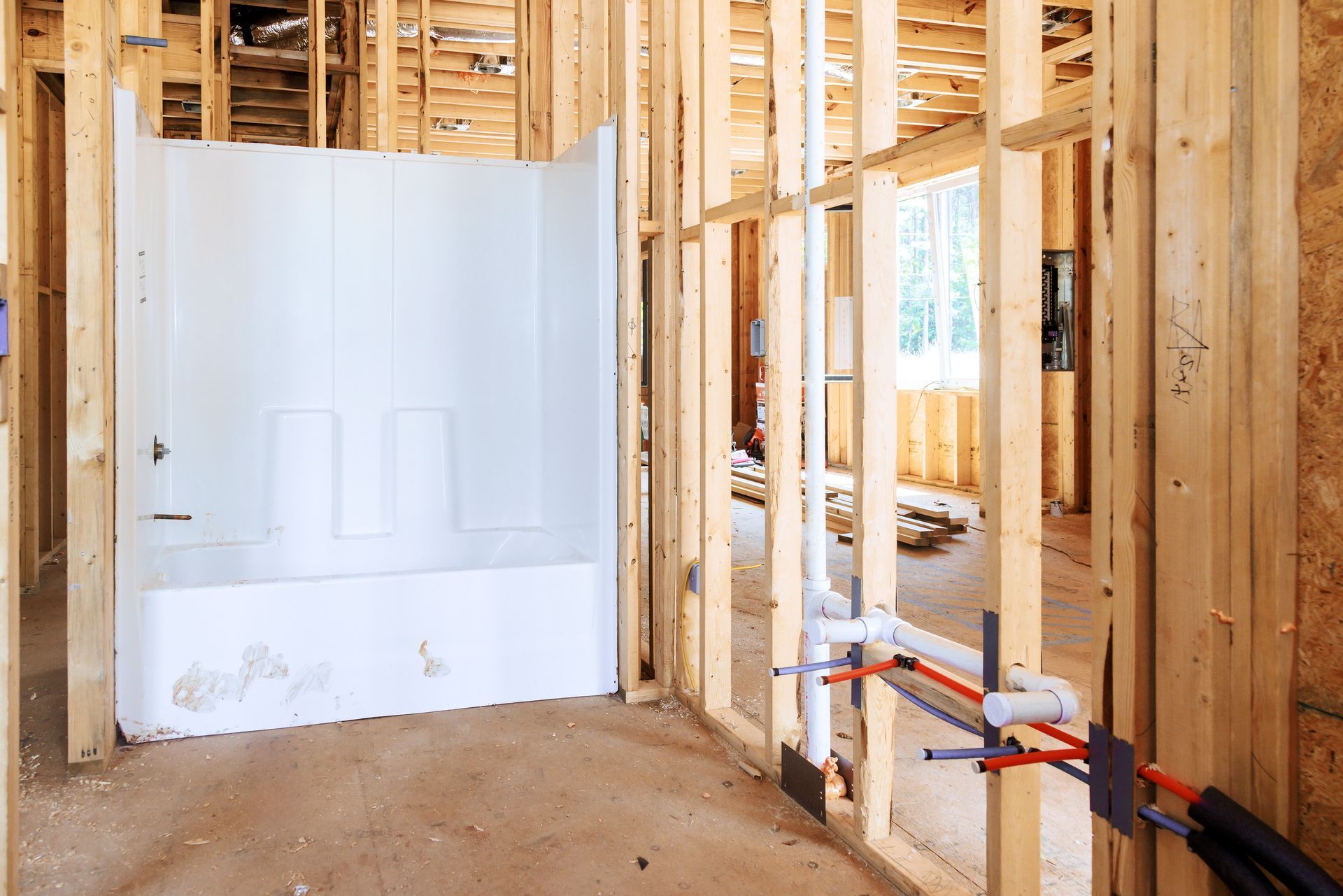 Unfinished bathroom with white shower surround and exposed wooden framing in a new home construction